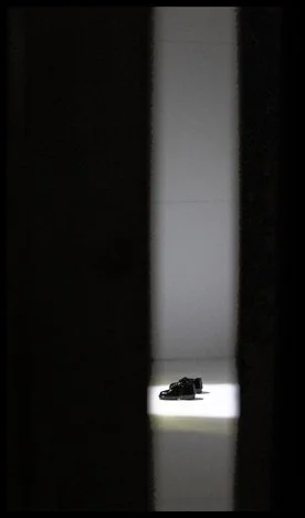 theatrical curtain pulled back to reveal a stage with two small shoes