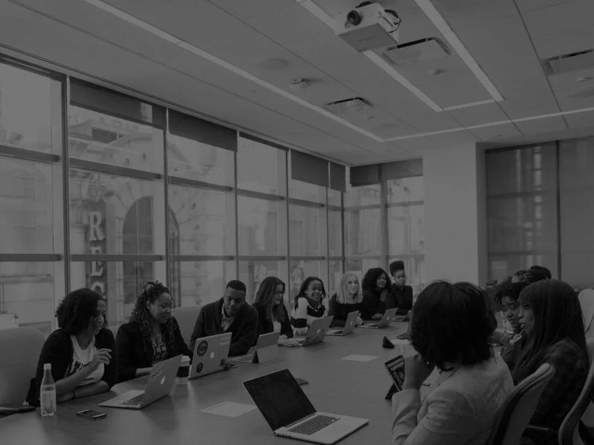 Boardroom full of people interacting with one another. Group discussion on resumes.