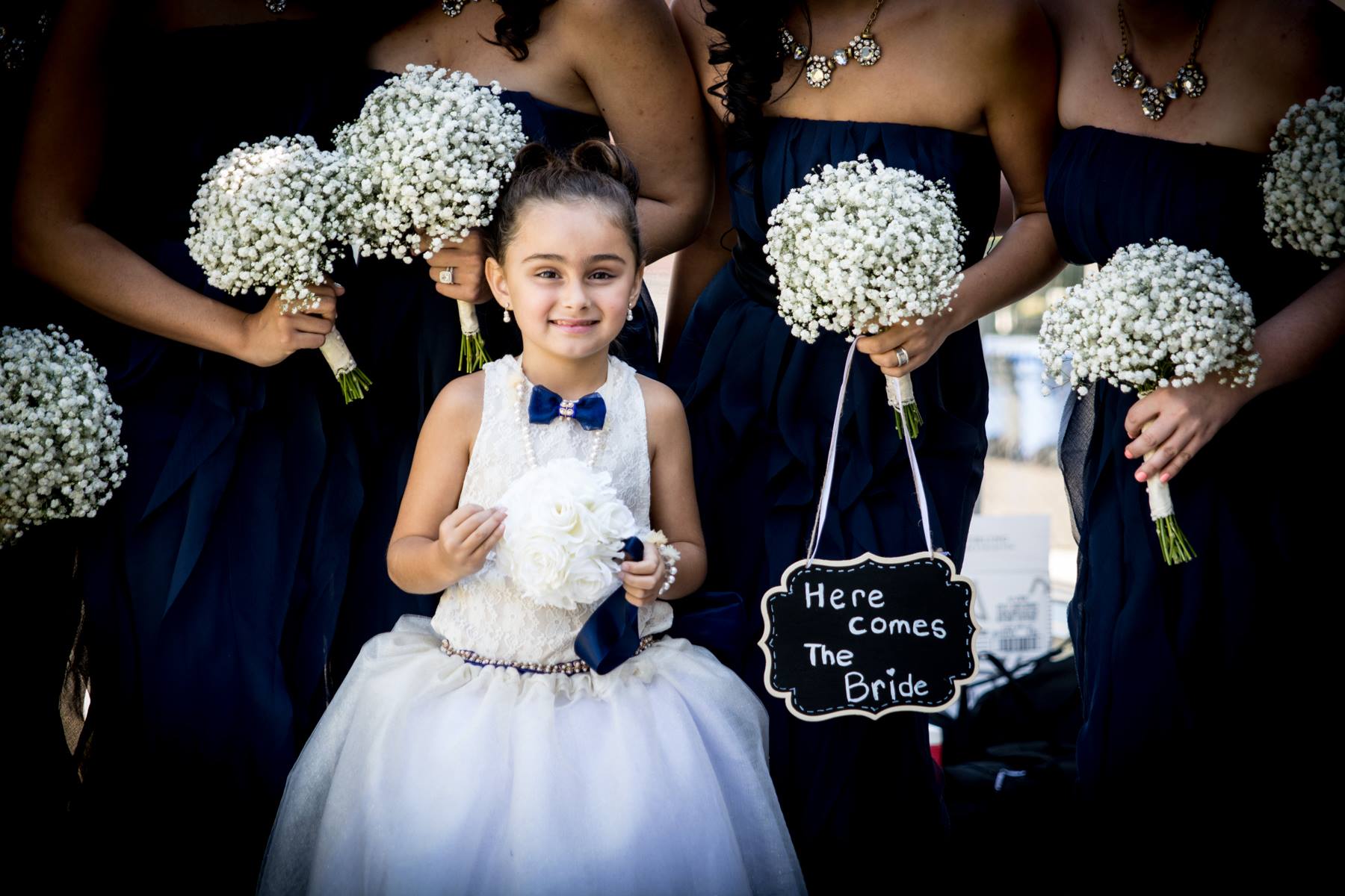 Flower girl with sign that says Here Comes The Bride