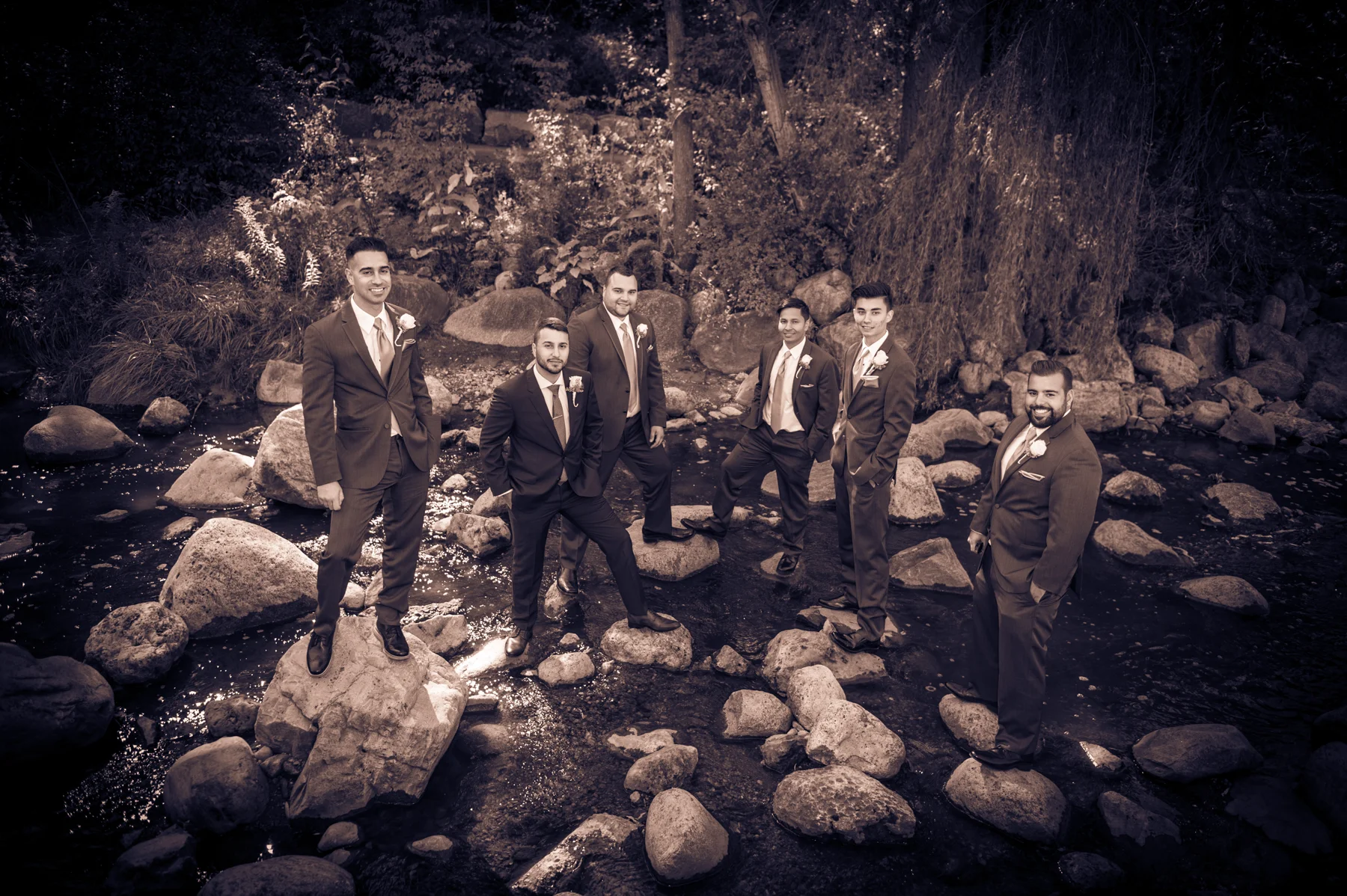 Groomsmen and Groom standing on rocks in the middle of the Don River at Edwards Gardens in Toronto