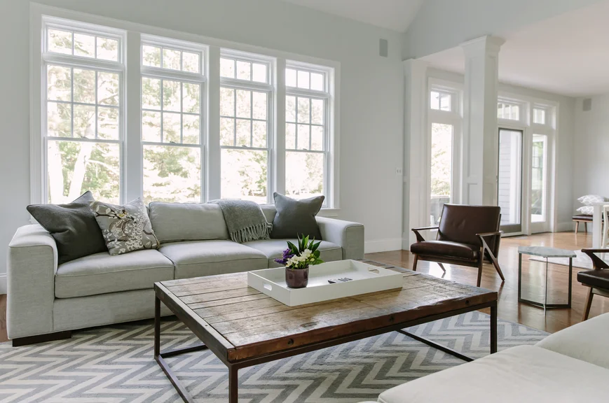 A living room designed by an interior designer with soft grays and whites as well as natural wood elements.