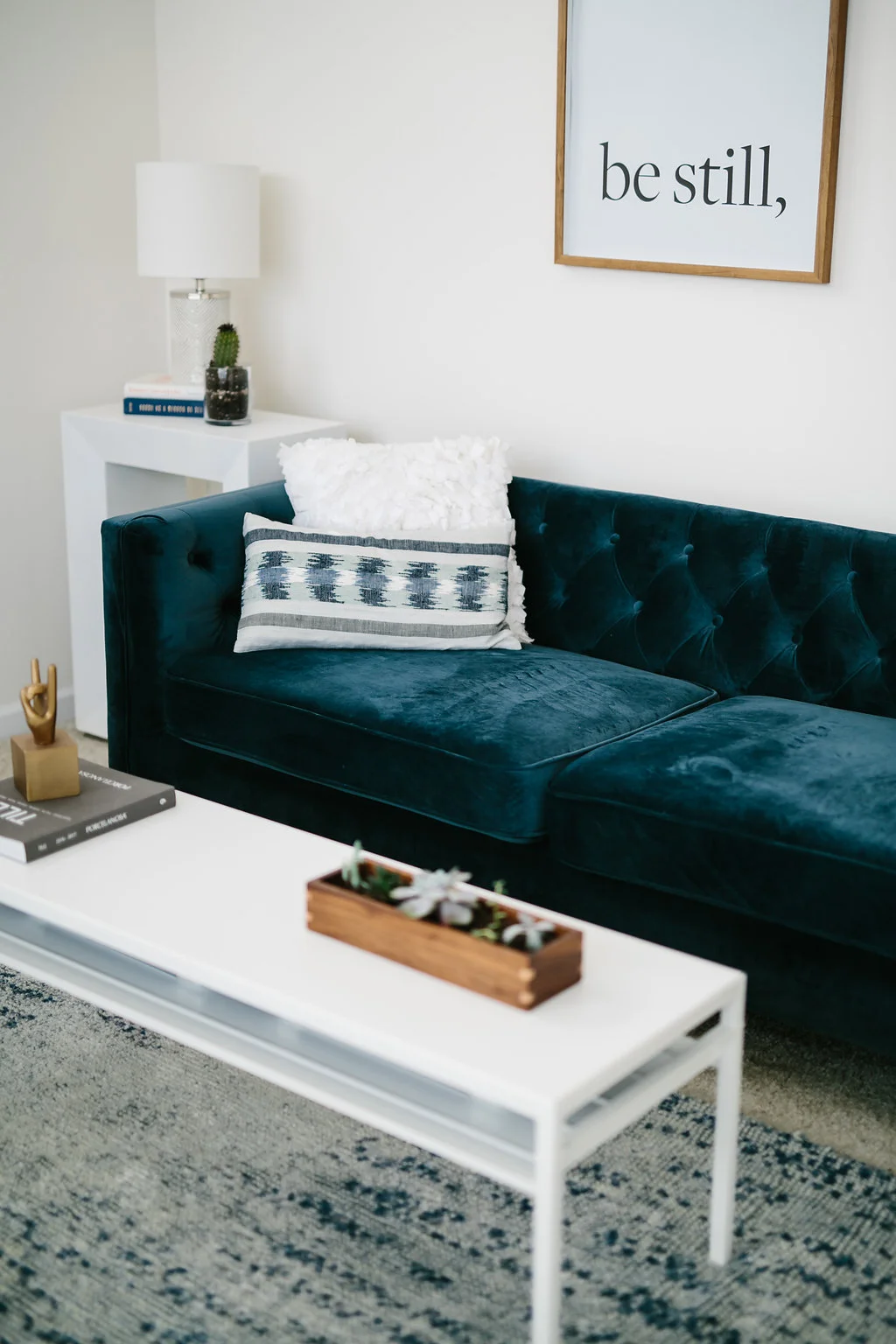 Tufted blue sofa and white coffee table with decor accents.