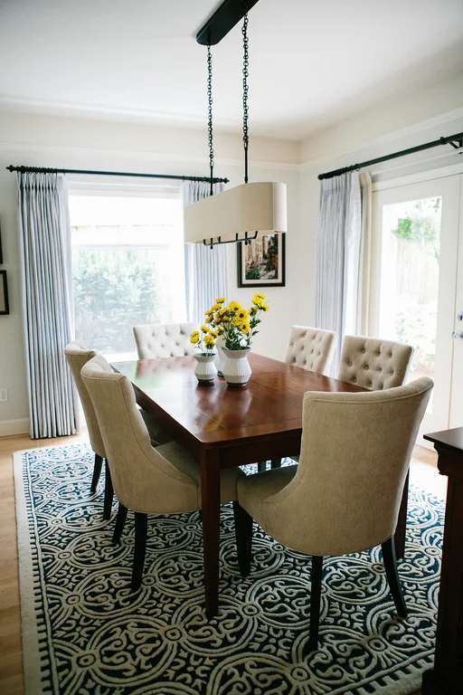 A wood parsons style dining table with tufted dining chairs and a patterned rug.