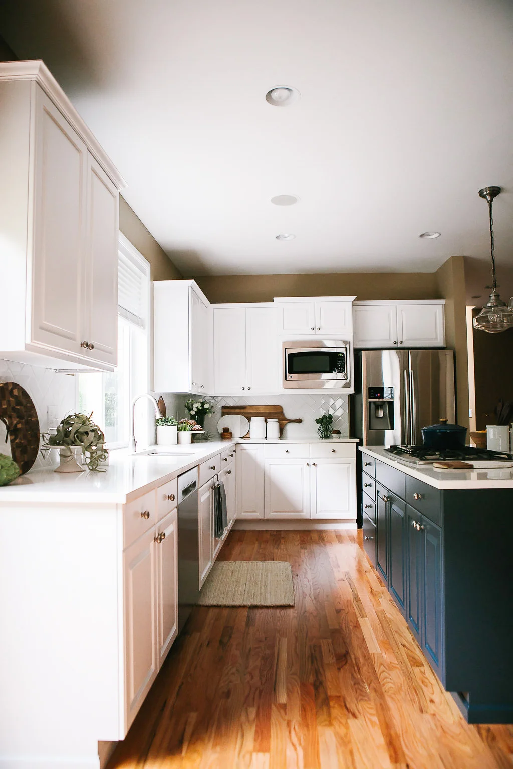 A transitional white kitchen with navy blue island designed by Elegant Simplicity.