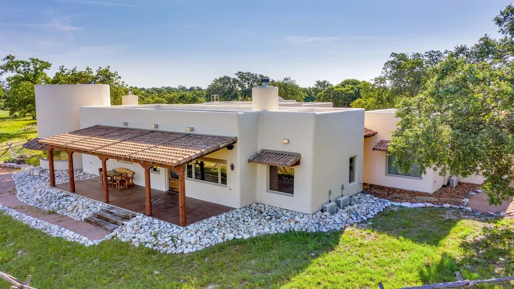 A white house featuring a covered patio and a spacious green yard, showcasing a serene outdoor environment.