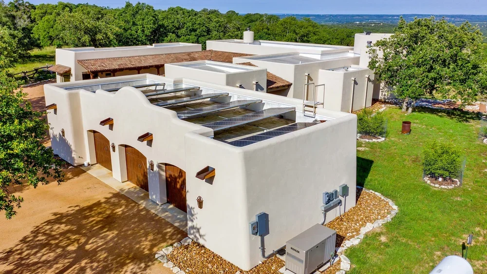  A white stucco house featuring a prominent, large roof against a clear blue sky.