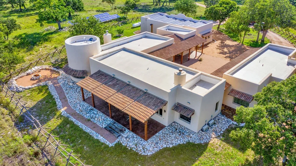  Aerial view of a rural home surrounded by fields and trees, showcasing the serene countryside landscape.
