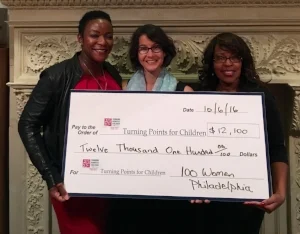 Eartha Holland, Development Director of Turning Points for Children (right) , and Dawn Holden, Turning Points' CFO (left) accept 100 Women Philadelphia's donation from its founder, Elizabeth Zack.