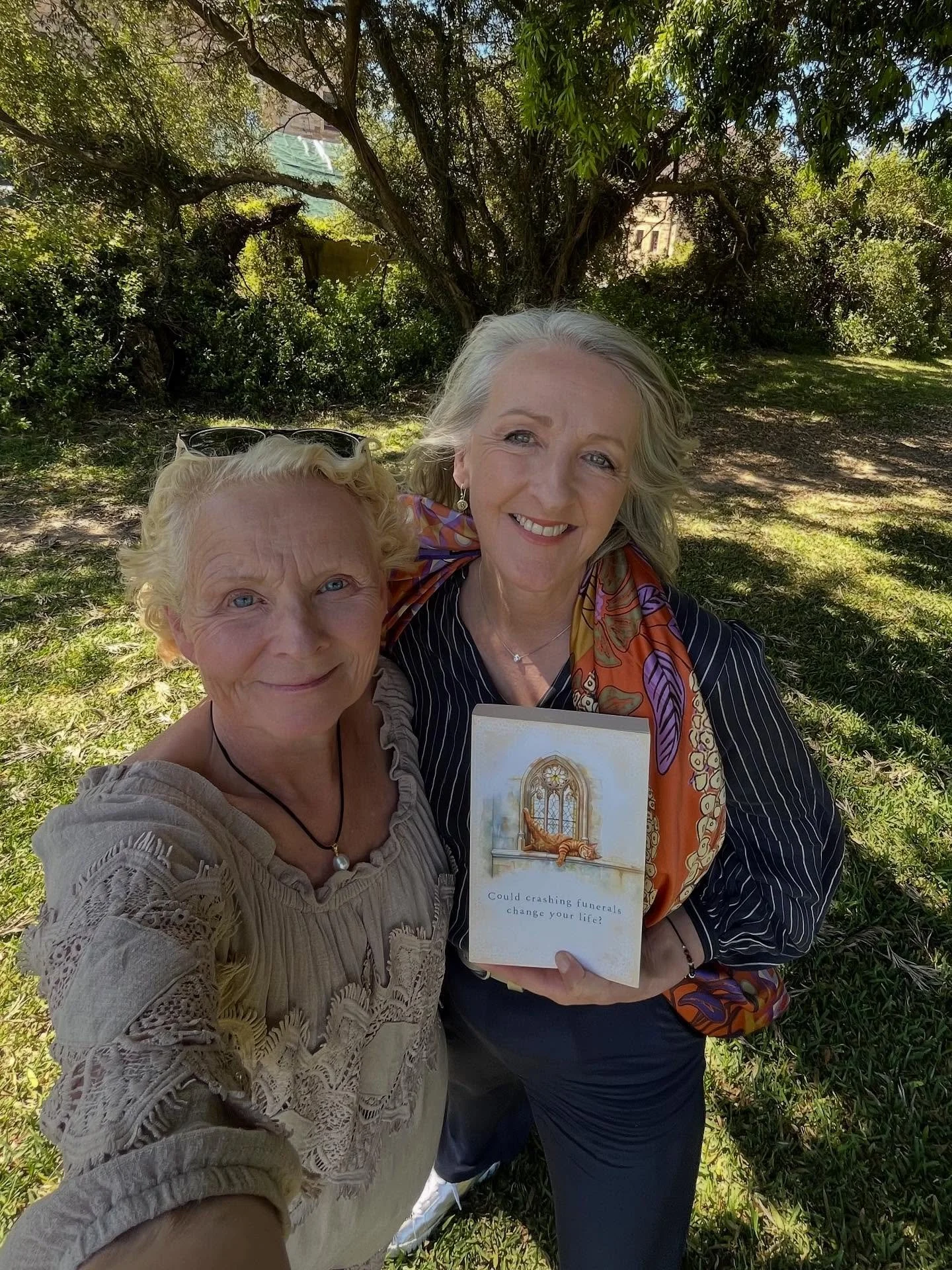 Two windswept women standing in a field of daisies excited to see you at Goulburn Library at 2pm on Tuesday 4 November to celebrate Joanna Nell&rsquo;s newest release, The Funeral Crashers, heartwarming, hilarious and all round wonderful is the story