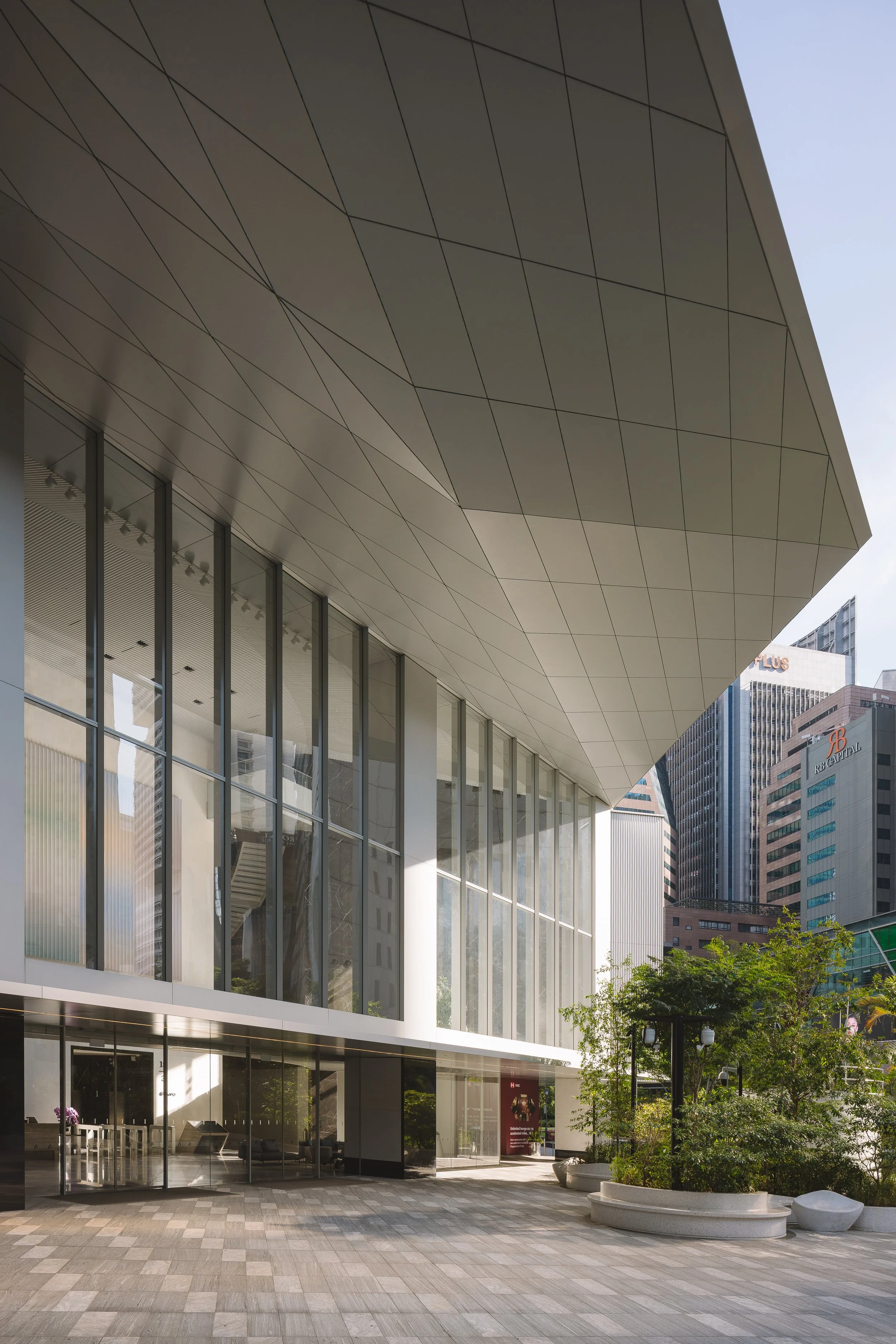 Singapore Land Tower in Singapore, showcasing the dramatic cantilevered entrance canopy, glazed façade and landscaped public plaza. Architectural photography by Daniel Koh.