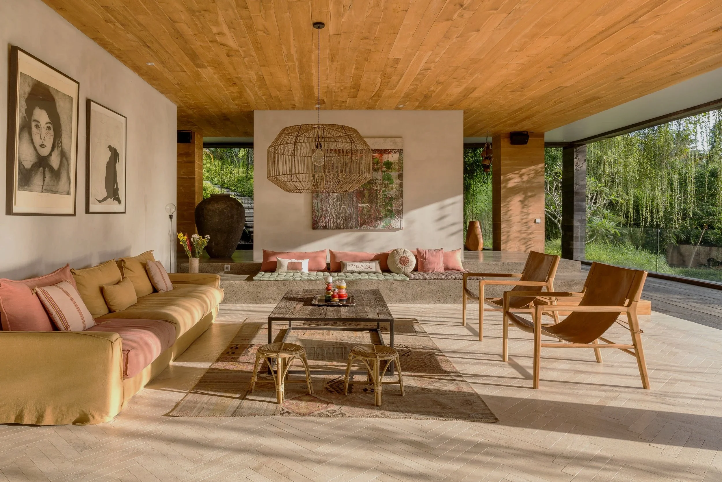 Architectural photography of the open-plan living pavilion at Villa Chameleon, Bali, featuring warm timber ceilings, handcrafted furnishings, natural stone finishes, and lush tropical garden views.