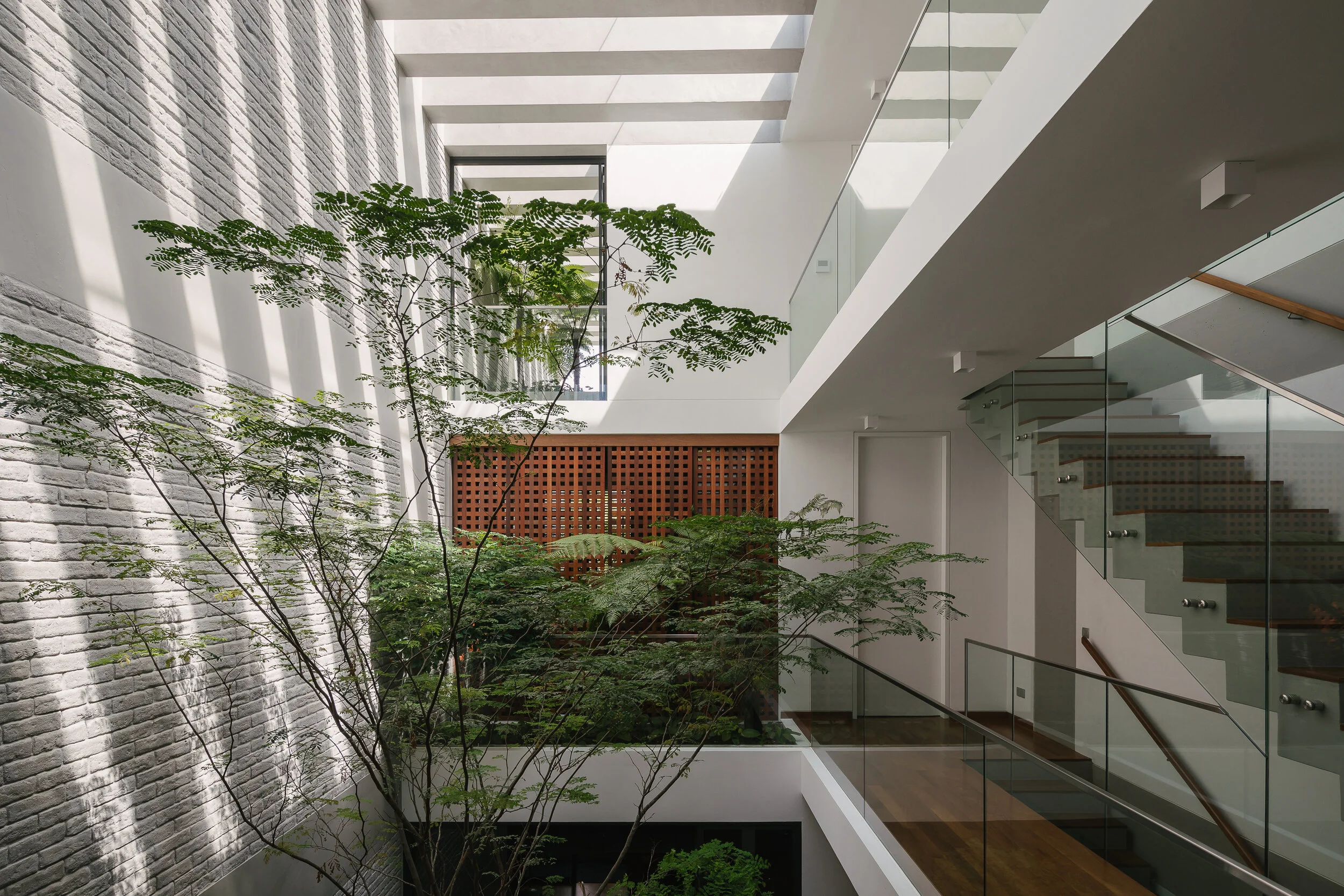 Award-winning residential architecture by HYLA Architects featuring a lush internal courtyard, natural daylight, glass bridges and tropical landscaping, photographed by Daniel Koh.