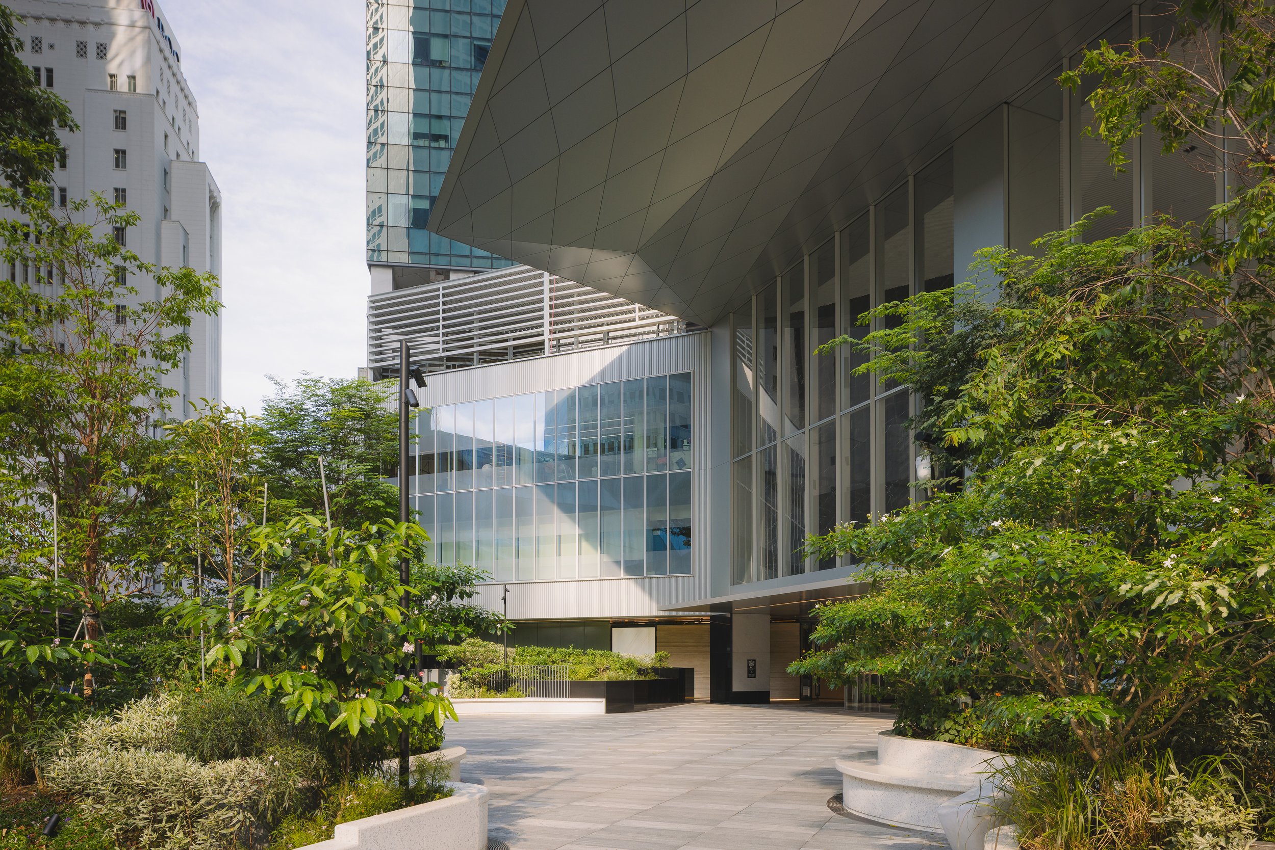 Singapore Land Tower in Singapore, featuring the landscaped entrance plaza by Henning Larsen, lush planting, dramatic cantilevered canopy and contemporary glass façade. Architectural photography by Daniel Koh.