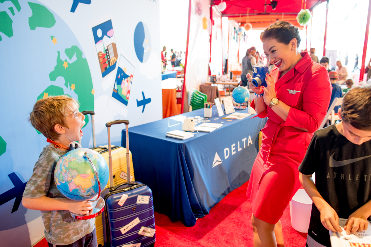 A guest excitedly poses in front of the backdrop while a flight attendant takes his photo!