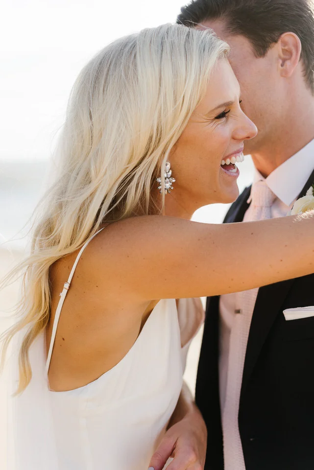 Bride looks radiant laughing with her groom on the beach at Palm beach