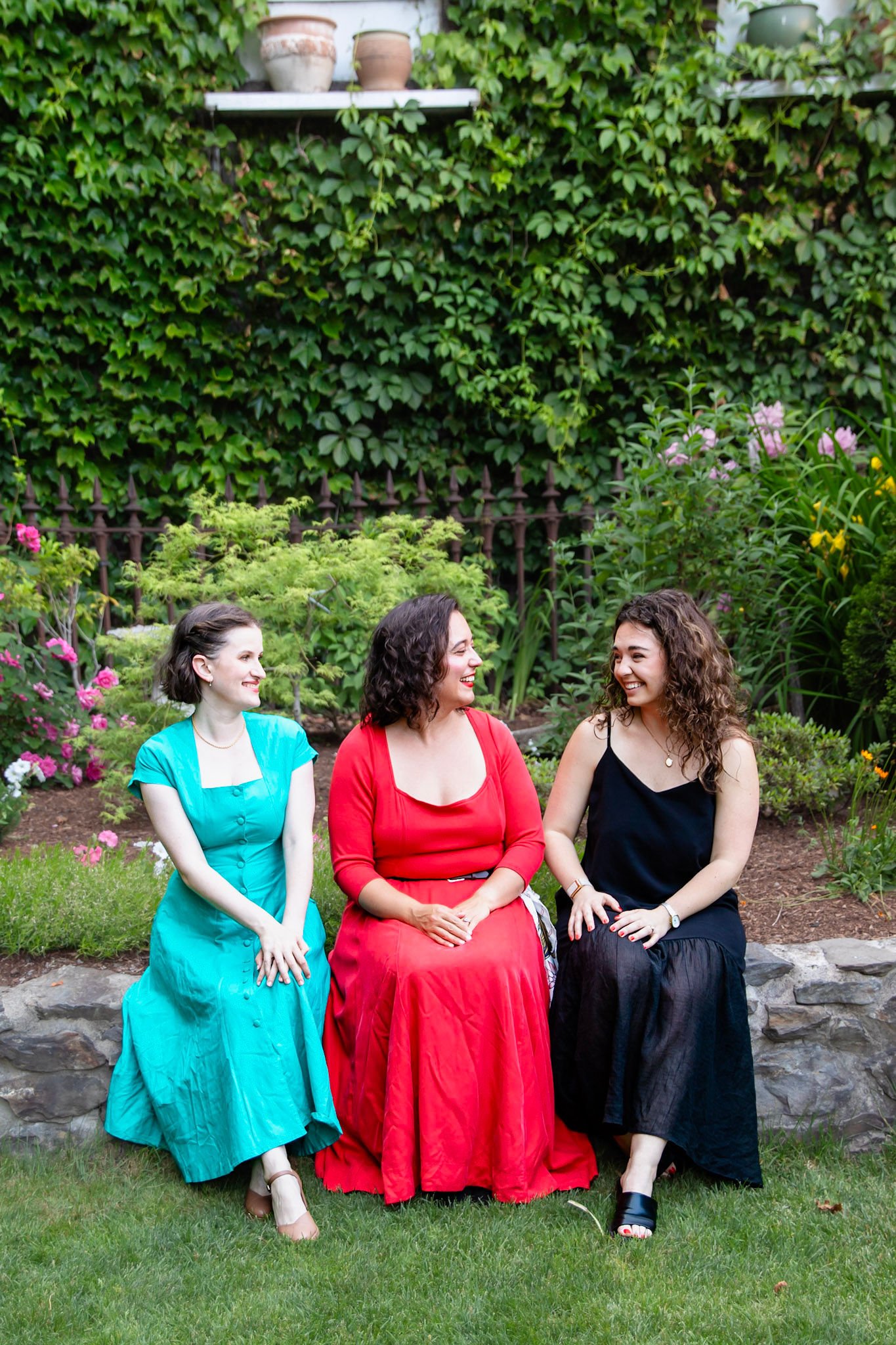 Isabel, Sylvia and Katelyn sitting on a brick wall smiling at each other