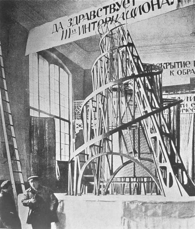 Vladimir Tatlin (with pipe) before a wooden model of his tower, St. Petersburg, 1920.