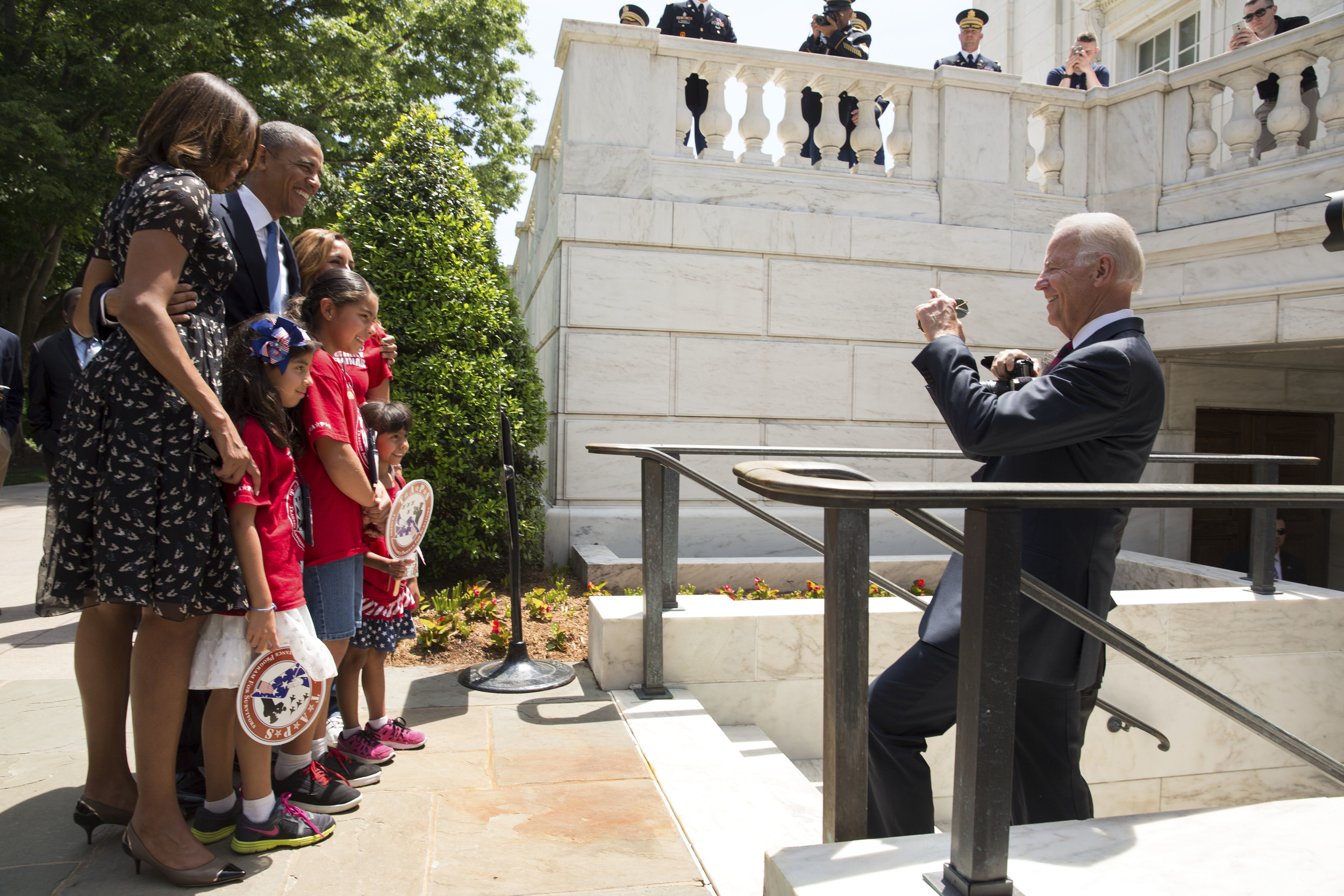 Vice President Joe Biden takes a photo with a cell phone of President Barack Obama, First Lady Michelle Obama, and TAPS Kids on departure from Arlington National Cemetery - 2014.