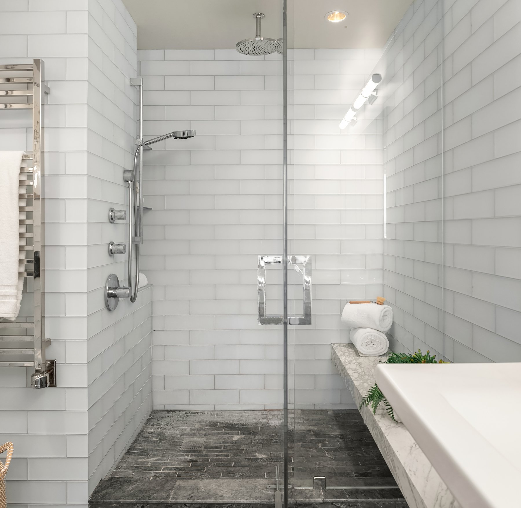  A close-up of the huge walk-in shower with a built-in bench and to the left, a towel warmer! 