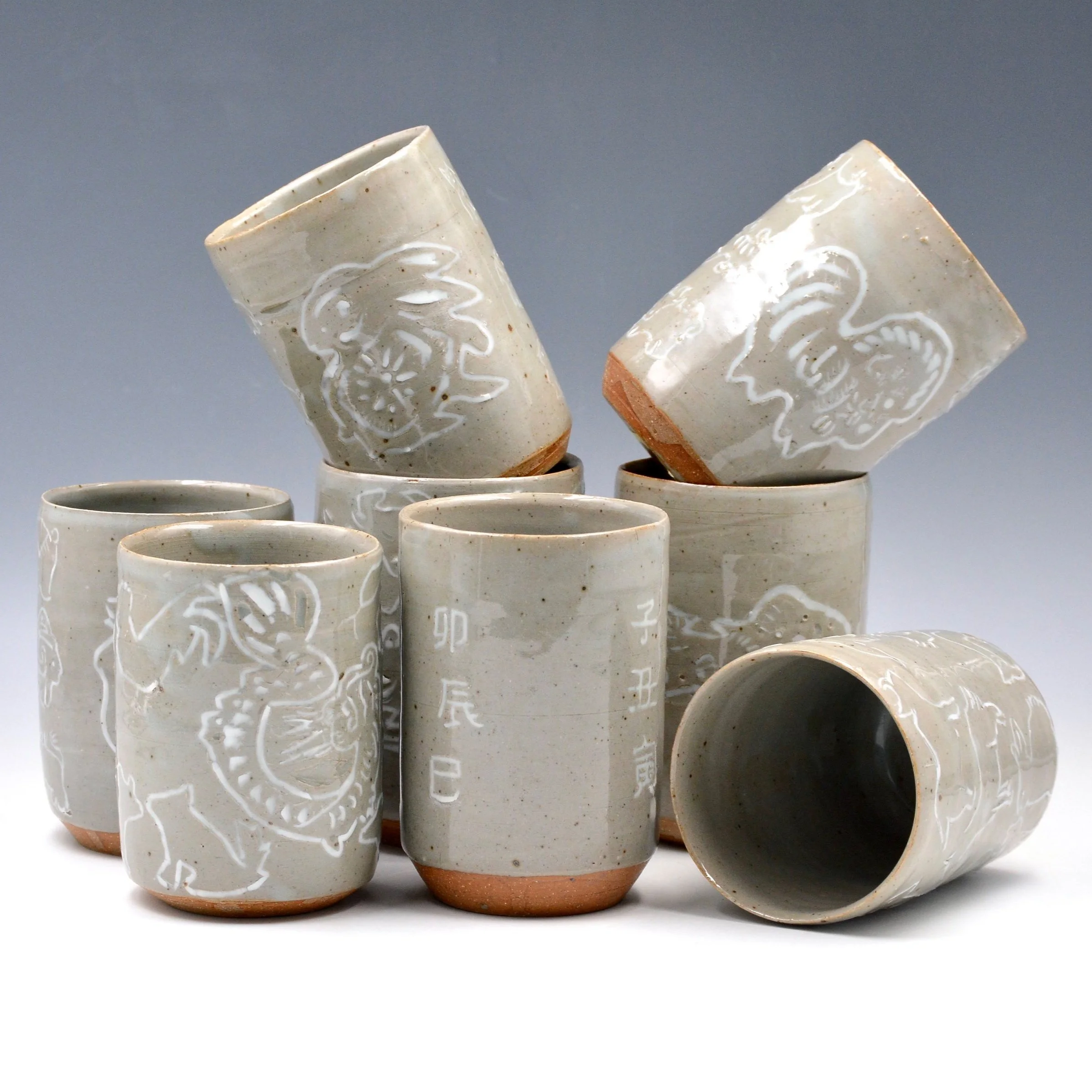 Group of ceramic cups with different Lunar New Year animals illustrated on them.
