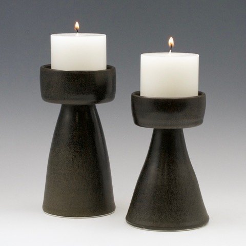 Come Together Candlesticks: two black candlesticks with flared bases and white lit candles.