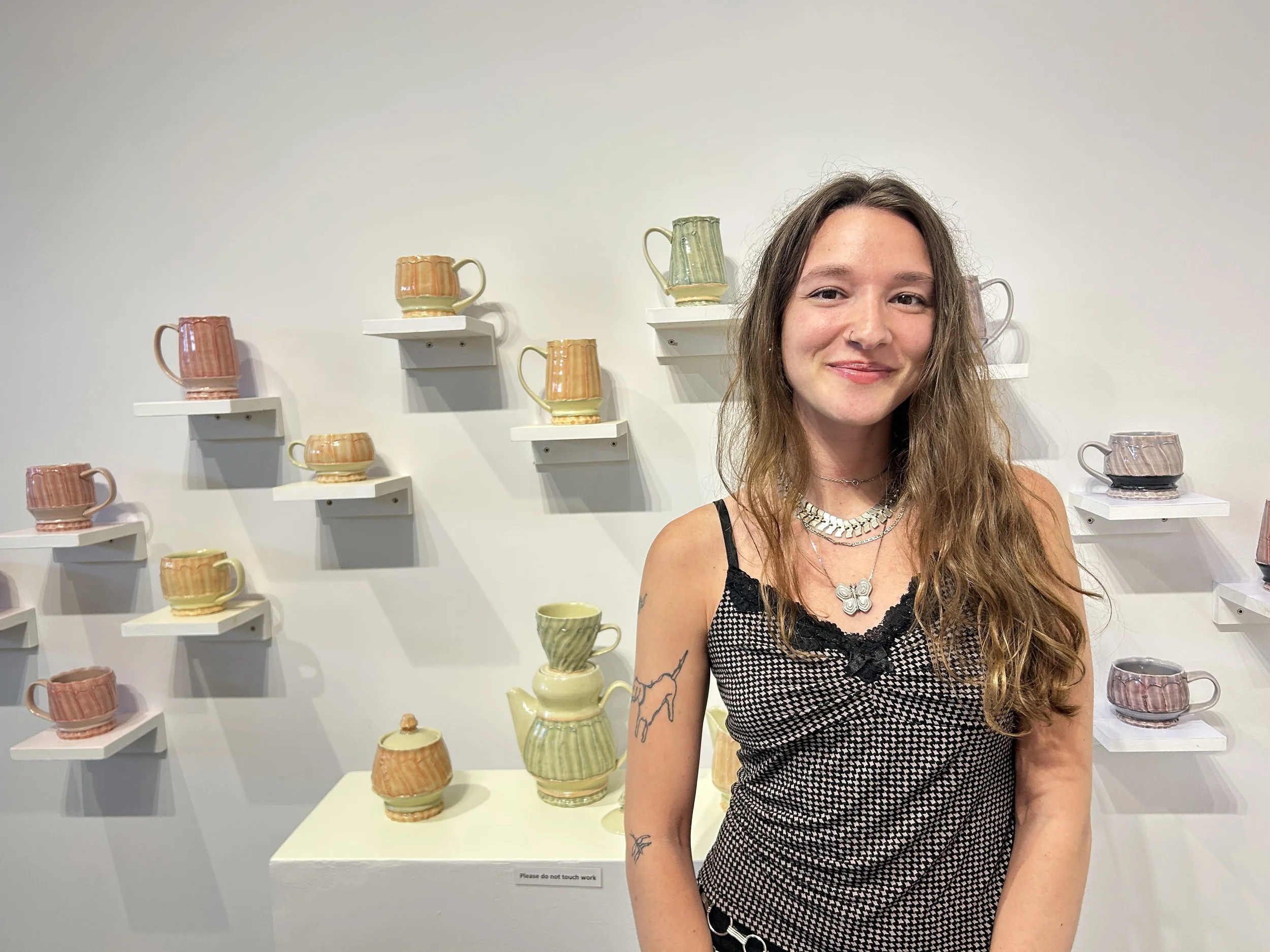 Carley stands in front of a wall of her pastel cups