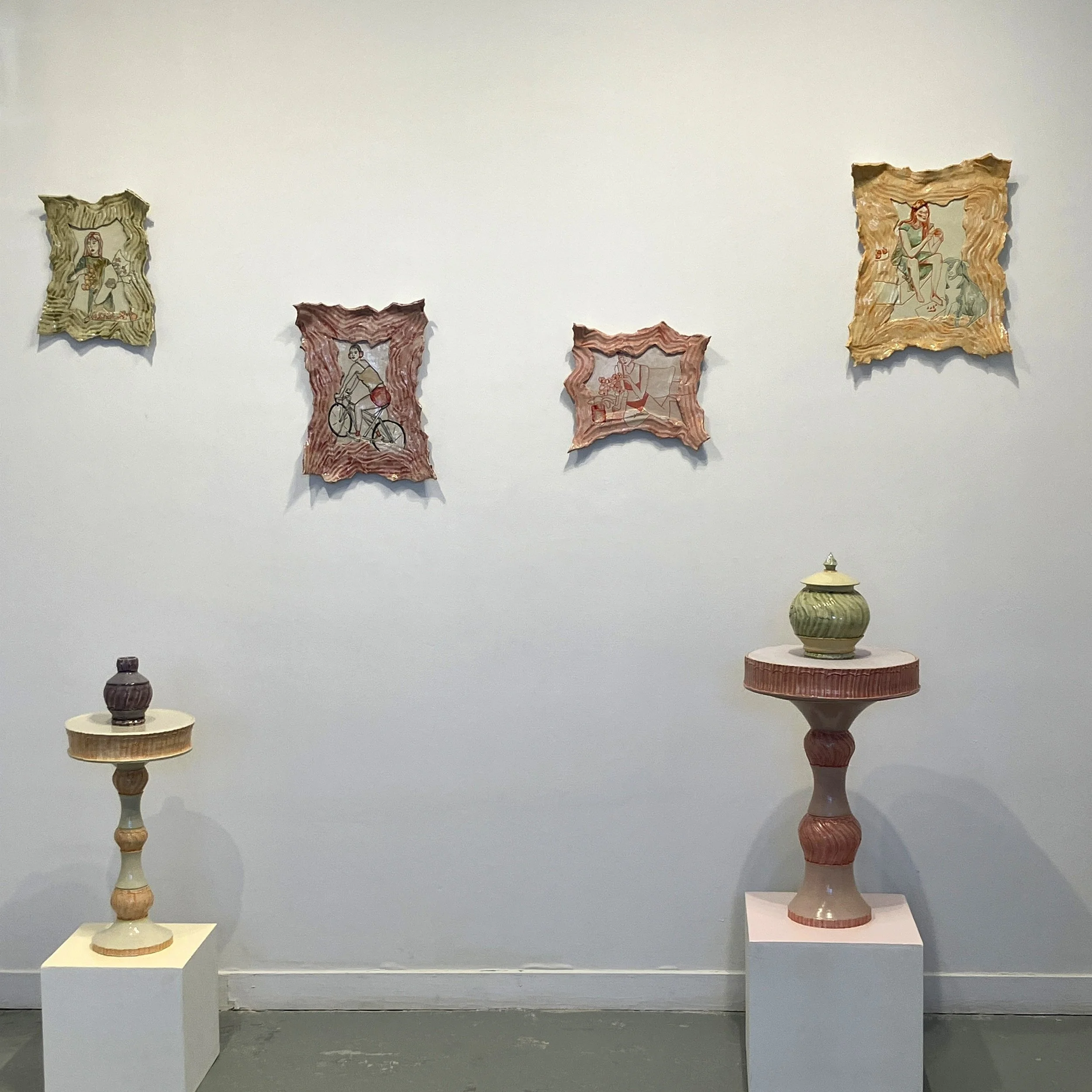 A view of the exhibition the Sunroom, showing Carley's four ceramic paintings, two tables, and two jars, all in pastel colors