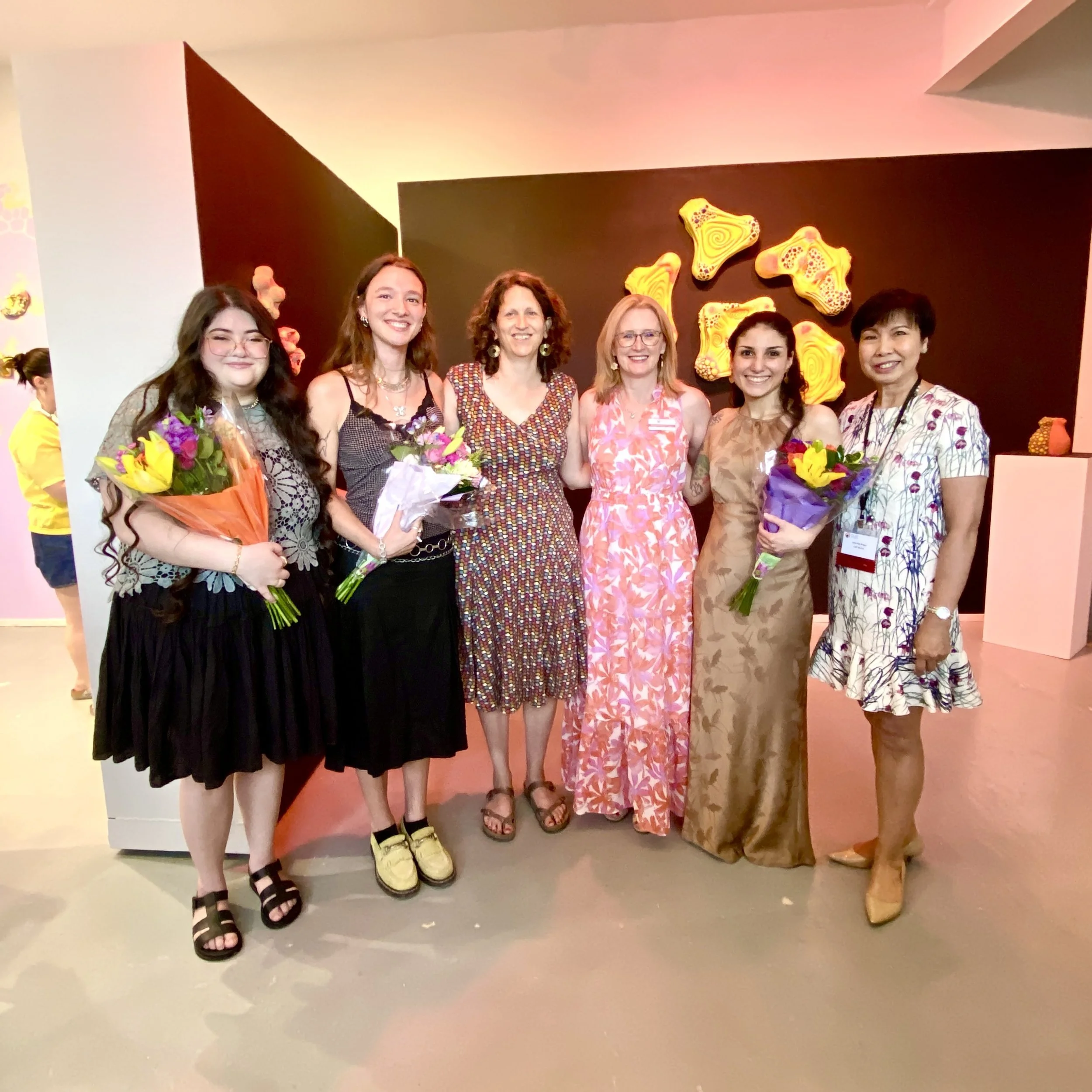 Resident Artists and staff stand smiling in front of the exhibition