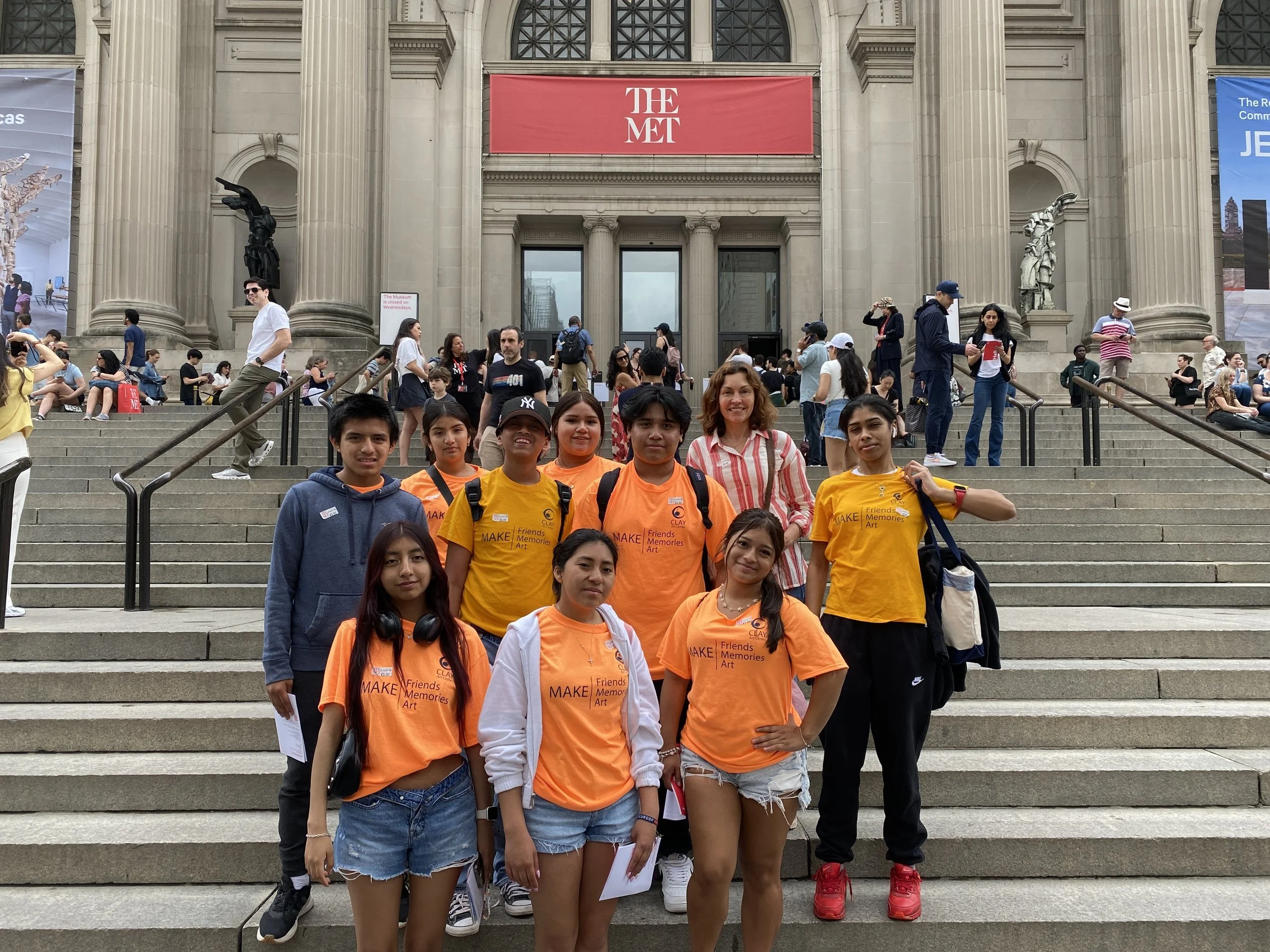 A group of teenage students stand together for a photo on the front steps of the Metropolitan Museum