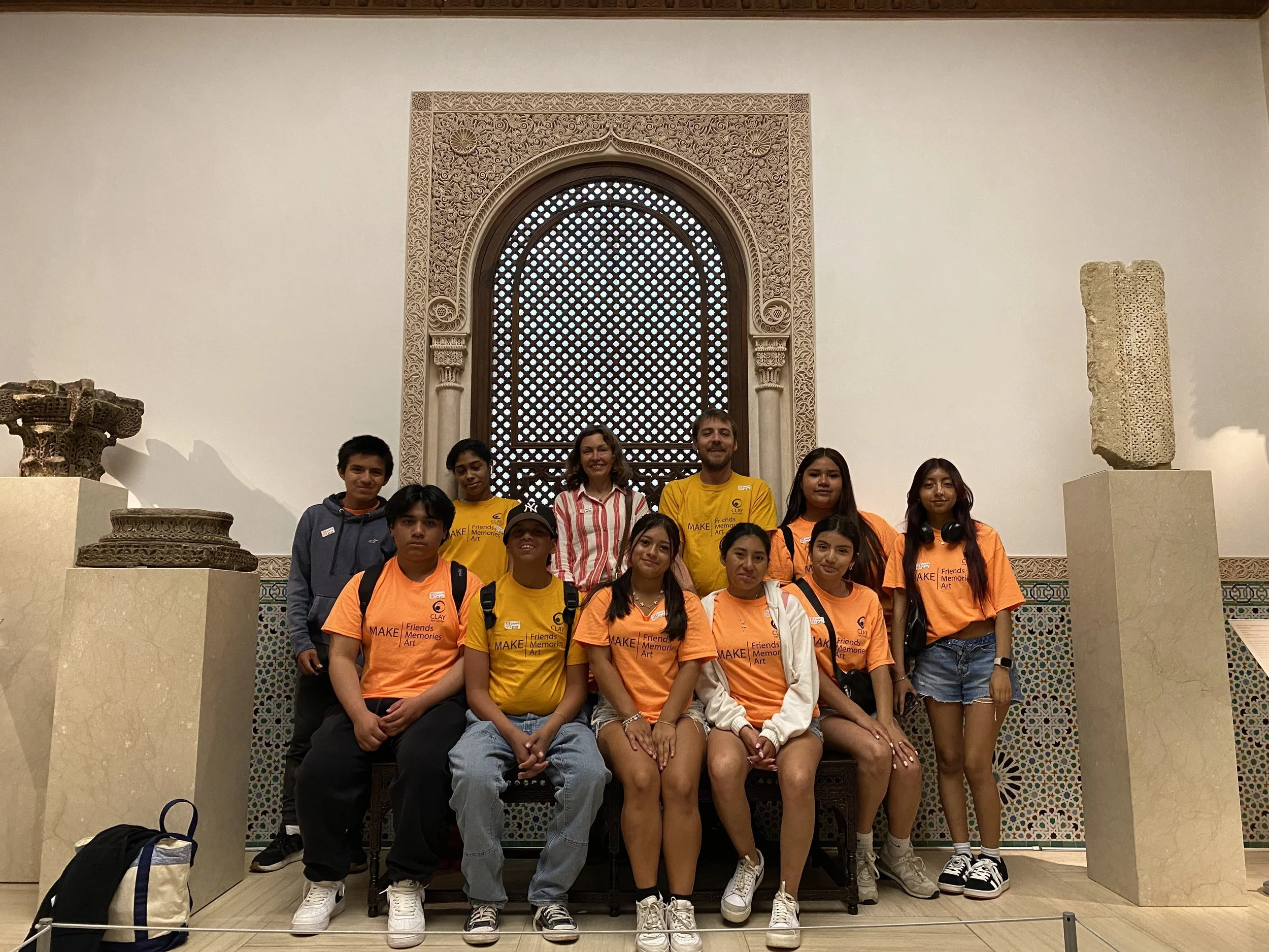 Group of students and their teachers sit in front of a historic tile mosaic at the Metropolitan Museum