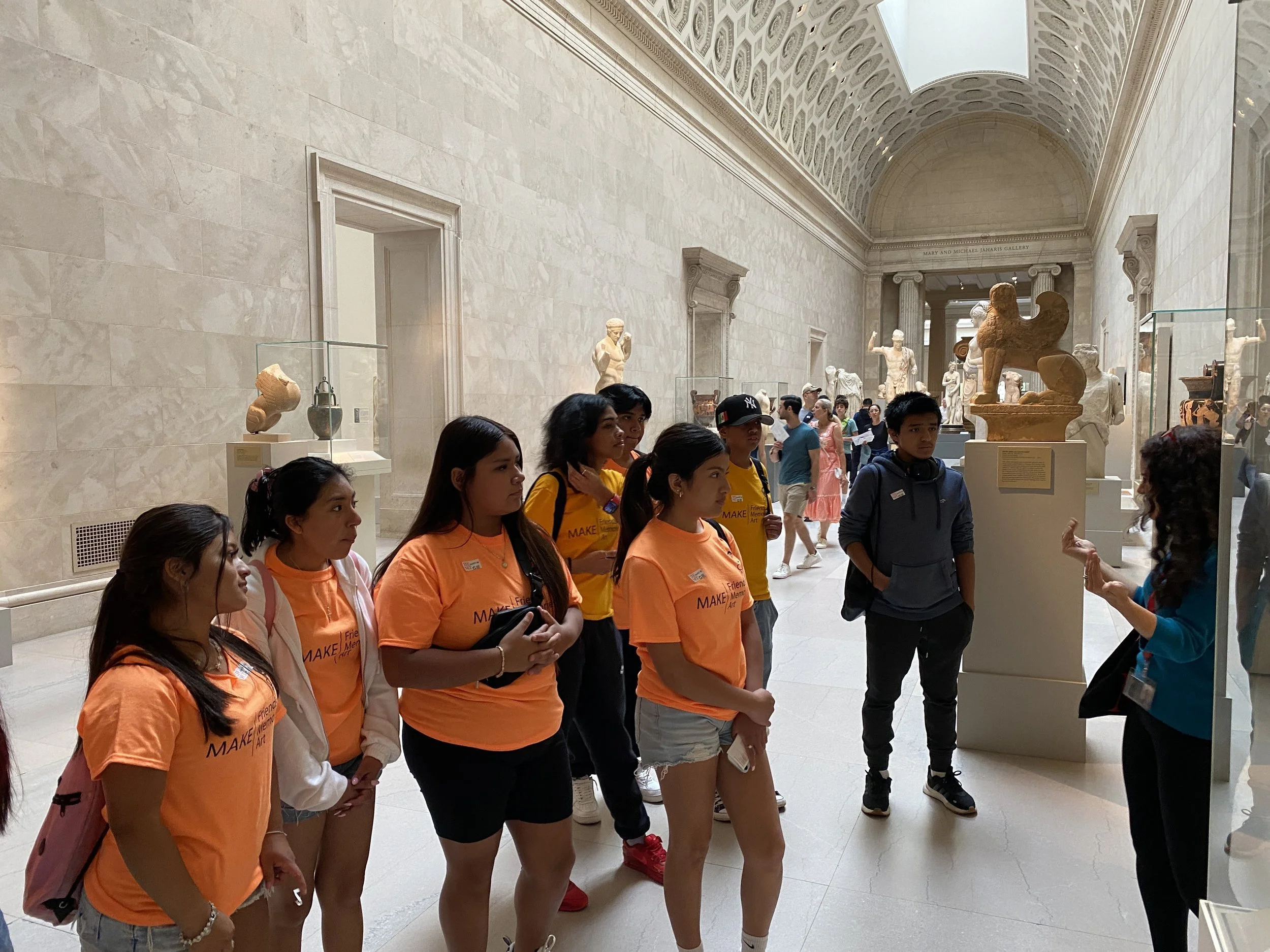 A group of students stands listening to a tour guide in the Metropolitan Museum