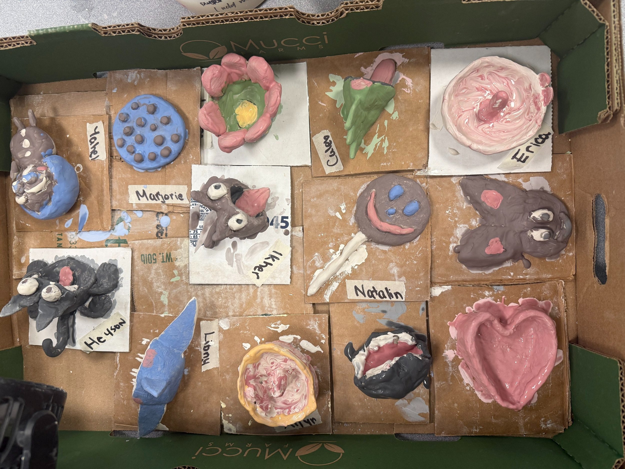 Zoomed in image of the box of pinch pot projects, including a flower, heart, ring dish, and other creatures