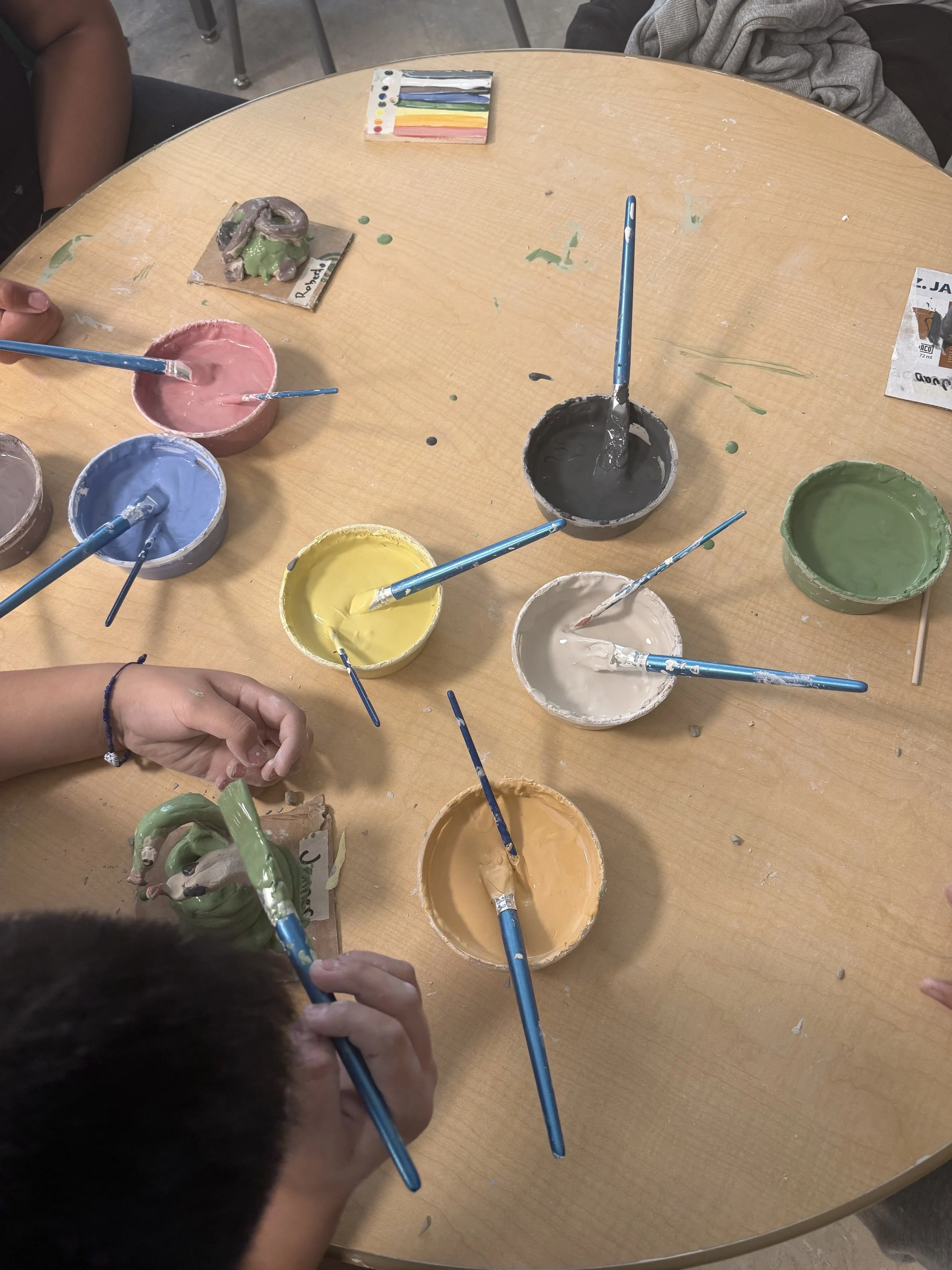 Students paint their projects from seven cups of brightly colored underglazes