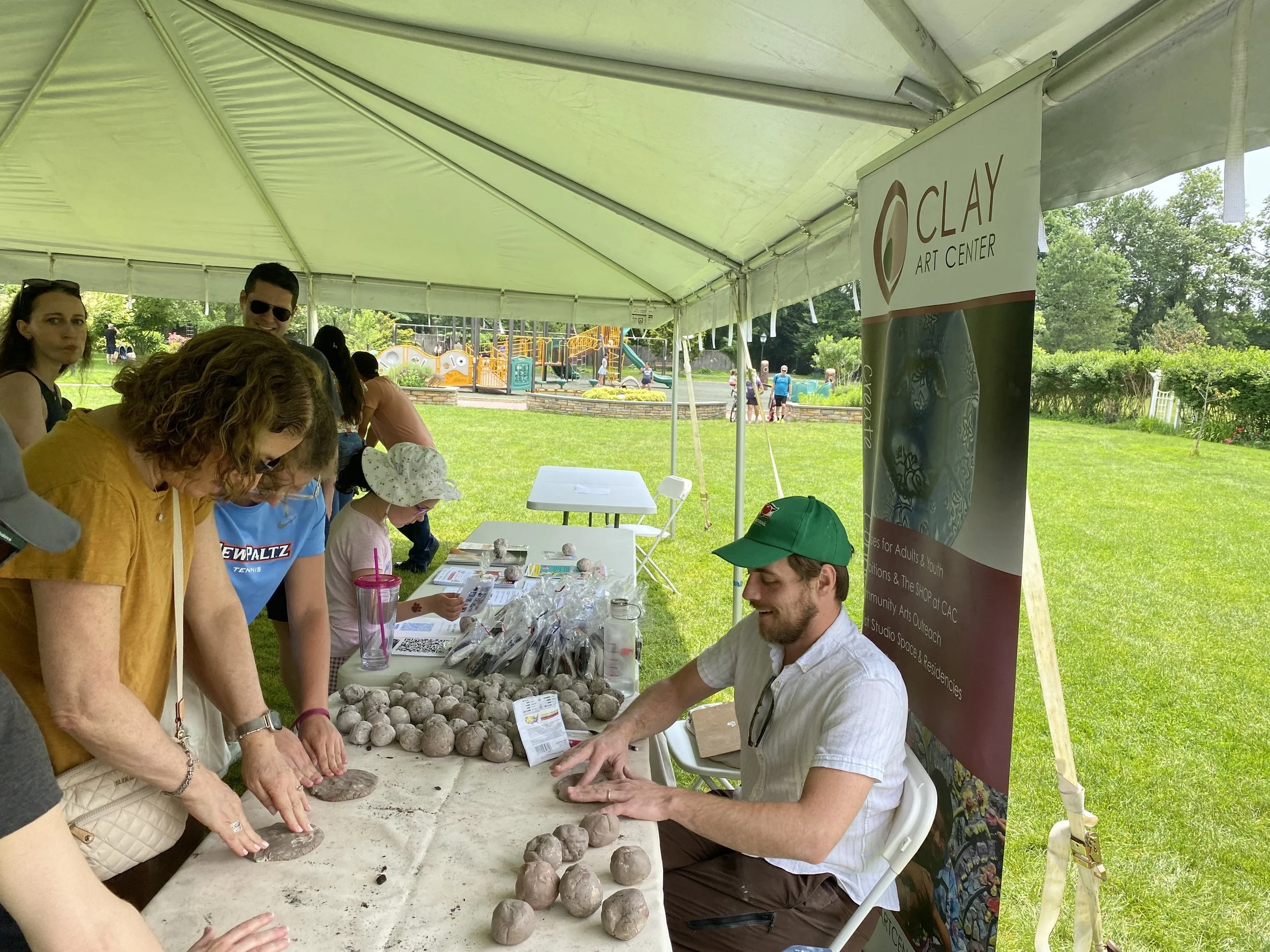 Brian shows a small crowd at his table how to make seed bombs with clay, soil, and seeds
