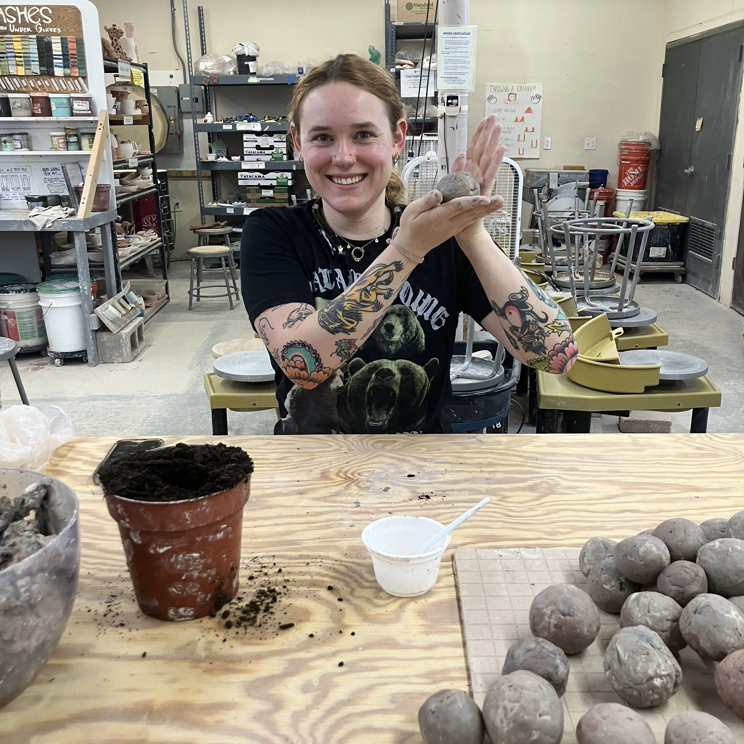 Sarah holds up the clay seed bomb she is rolling between her two hands