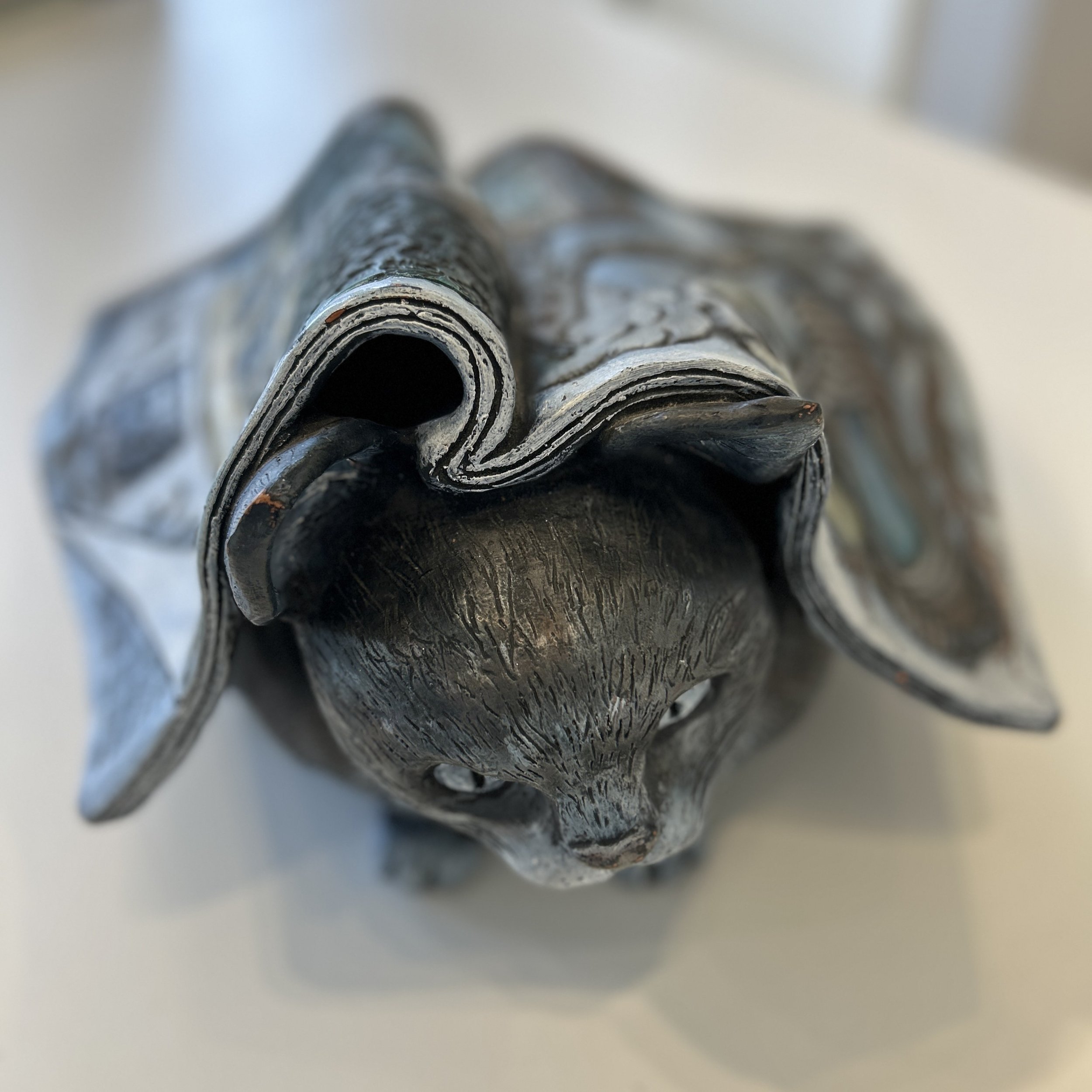 Front view of sculpture, showing top of cat's head under a Time magazine.