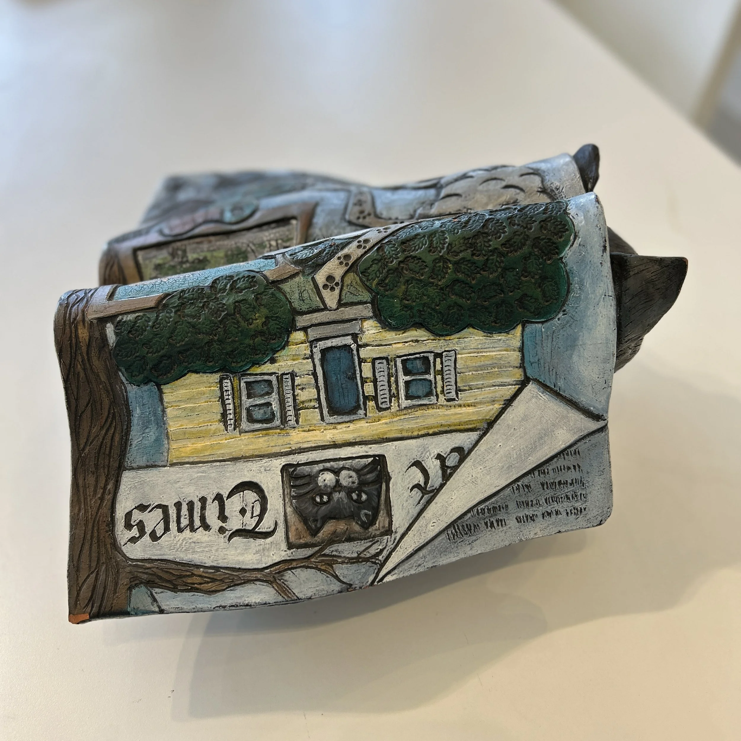 One of the splayed magazine pages on the sculpture, showing the top of a tree and a yellow house, as well as the word "Times"