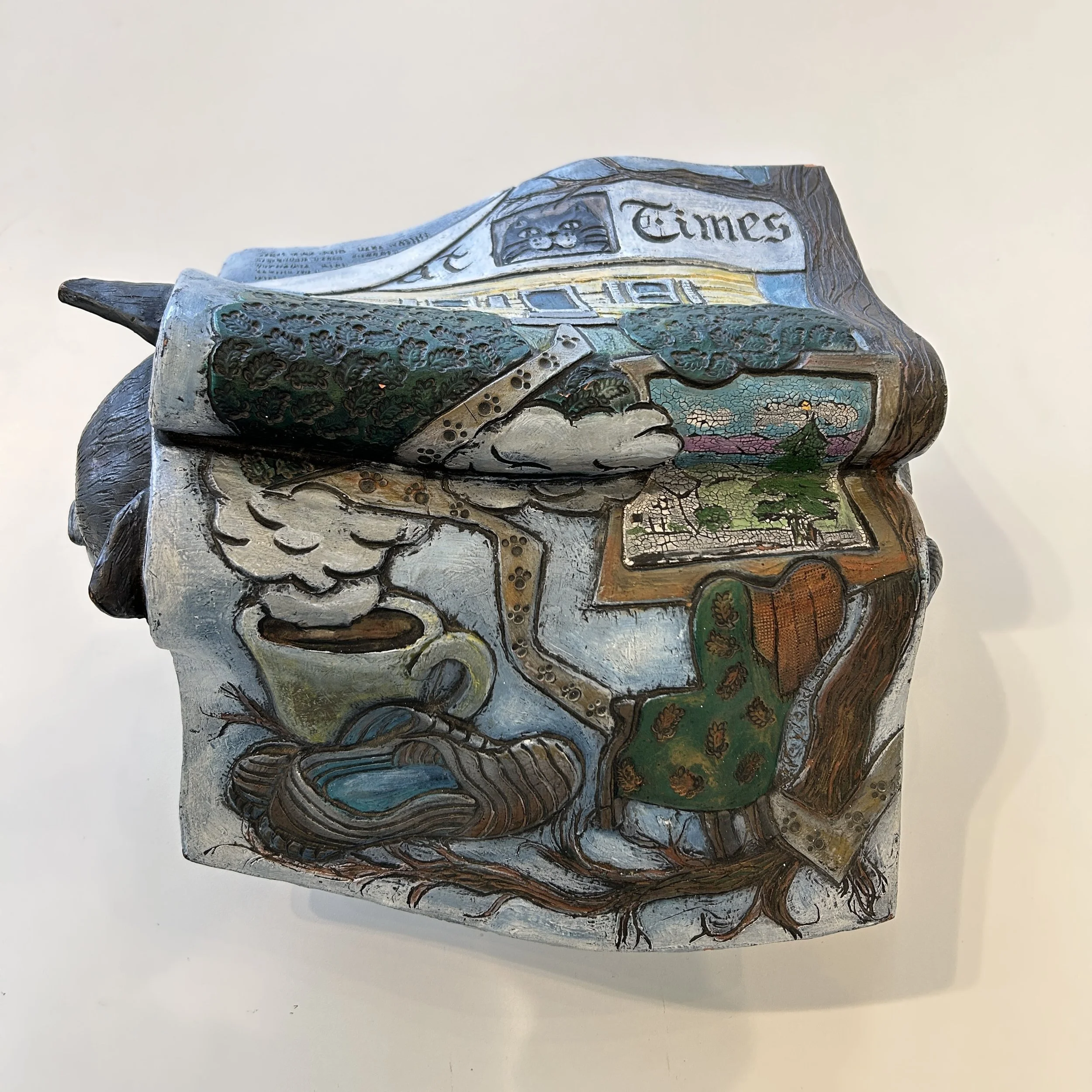 Splayed magazine page from the sculpture, showing a cup of coffee, a pair of slippers, and a green armchair.