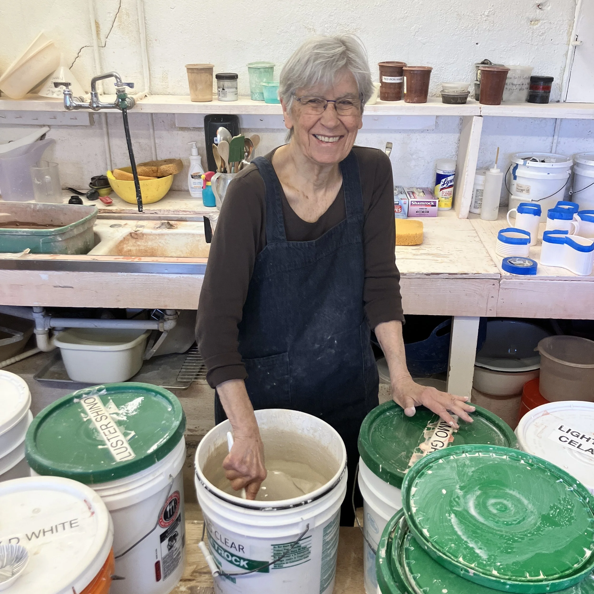 Dalia mixes the already-made glaze she is about to use in a five-gallon bucket.