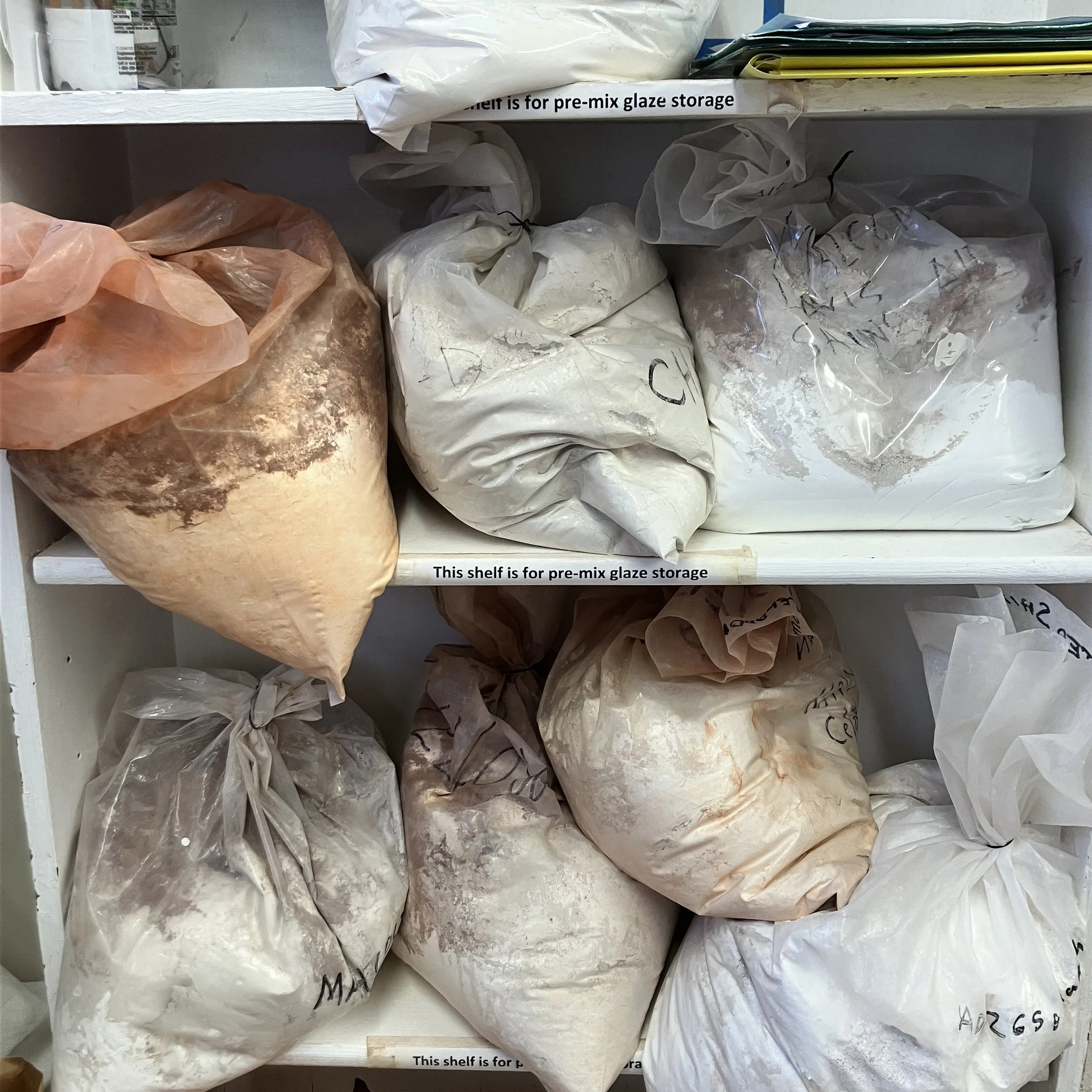A book shelf full of bags of pre-mixed glaze components in their powdered form.