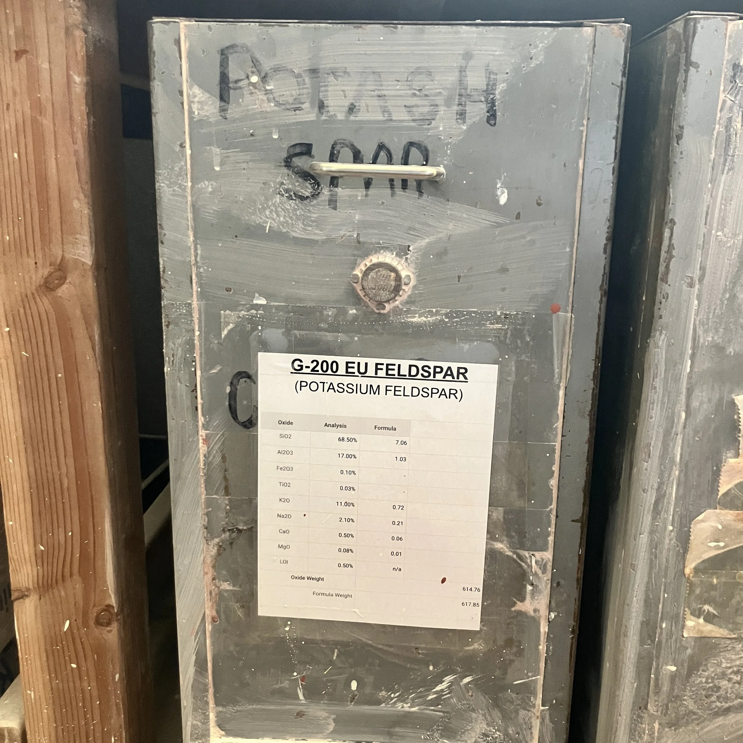 A close up image of the Potash Feldspar rolling bin that sits under the workbench. This now contains G-200 EU Feldspar, instead of Custer.