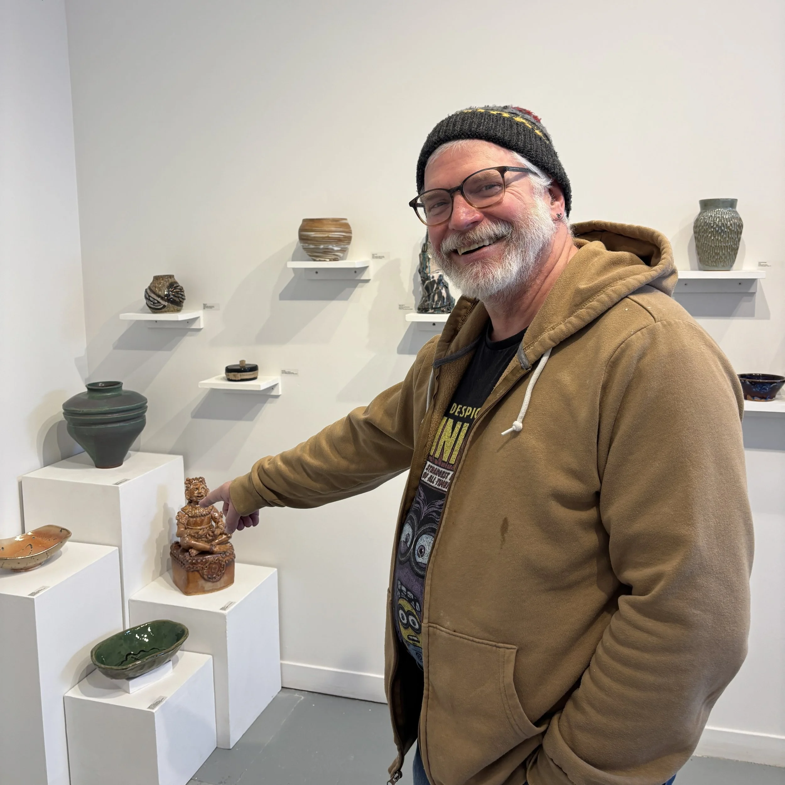 Jeff points to his sculpture of a seated prince figure, which is set on a pedestal among other ceramic pieces in the Rising Stars exhibition.