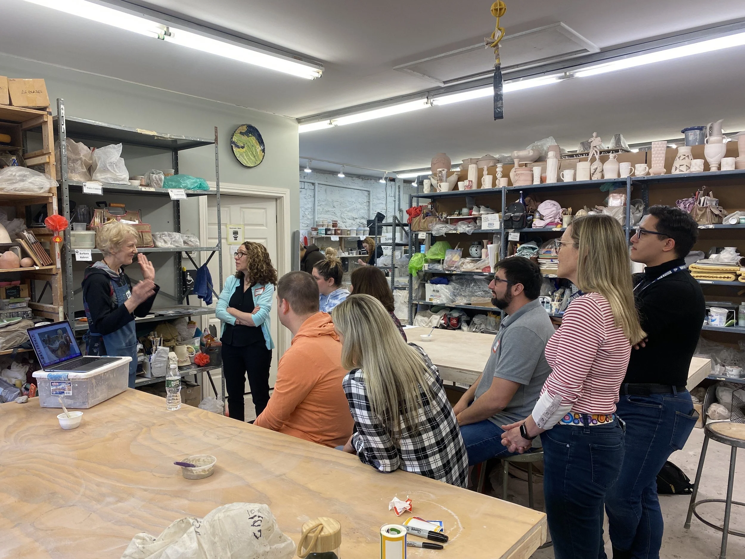 A group of Port Chester teachers looks on as teacher Denis instructs, demonstrating with her hands.