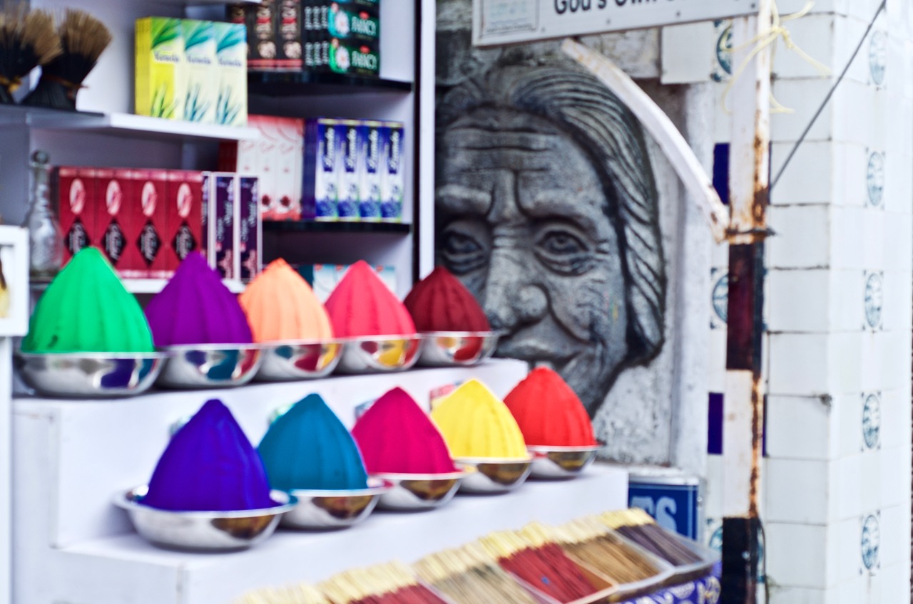 An old woman's face half-hidden by a modern store made pretty for tourists