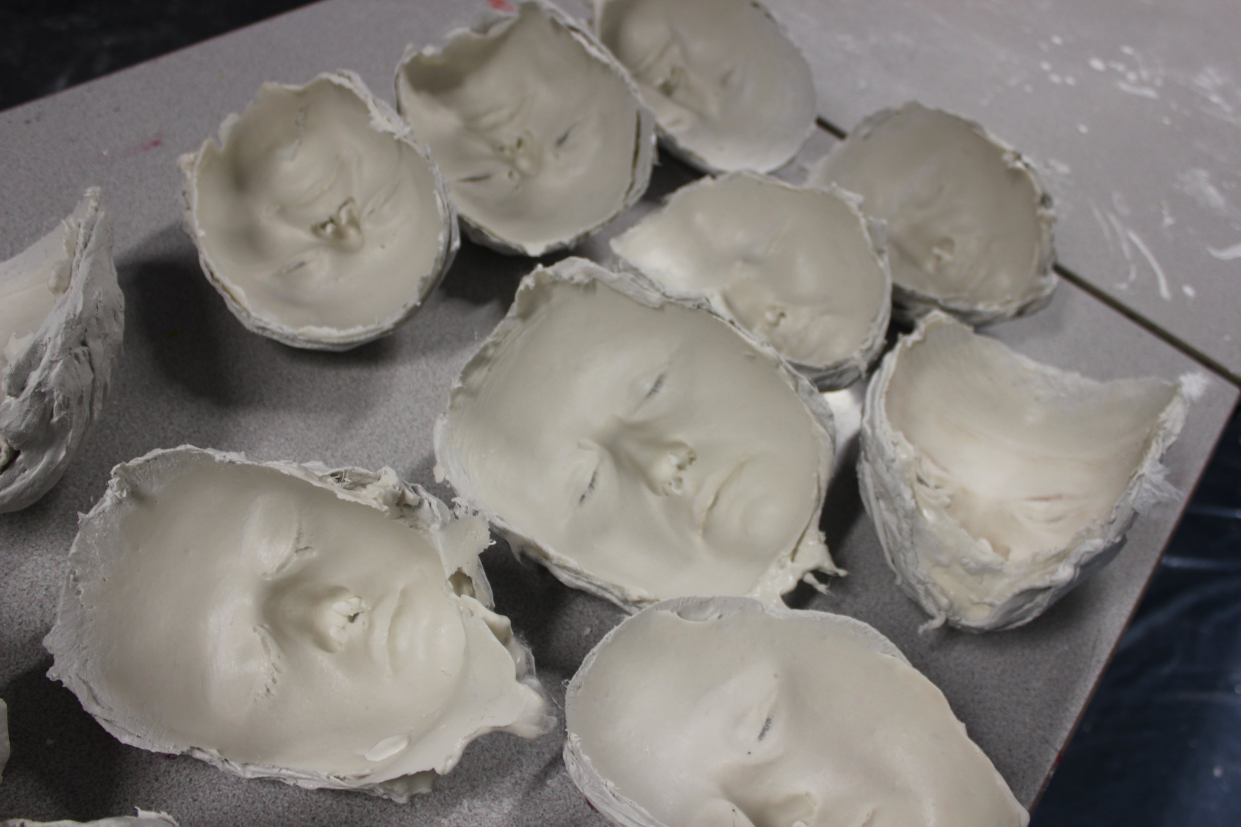 Multiple moulds waiting to be filled with plaster, from group face casting workshop at Invicta Grammar School for Girls, Kent. 