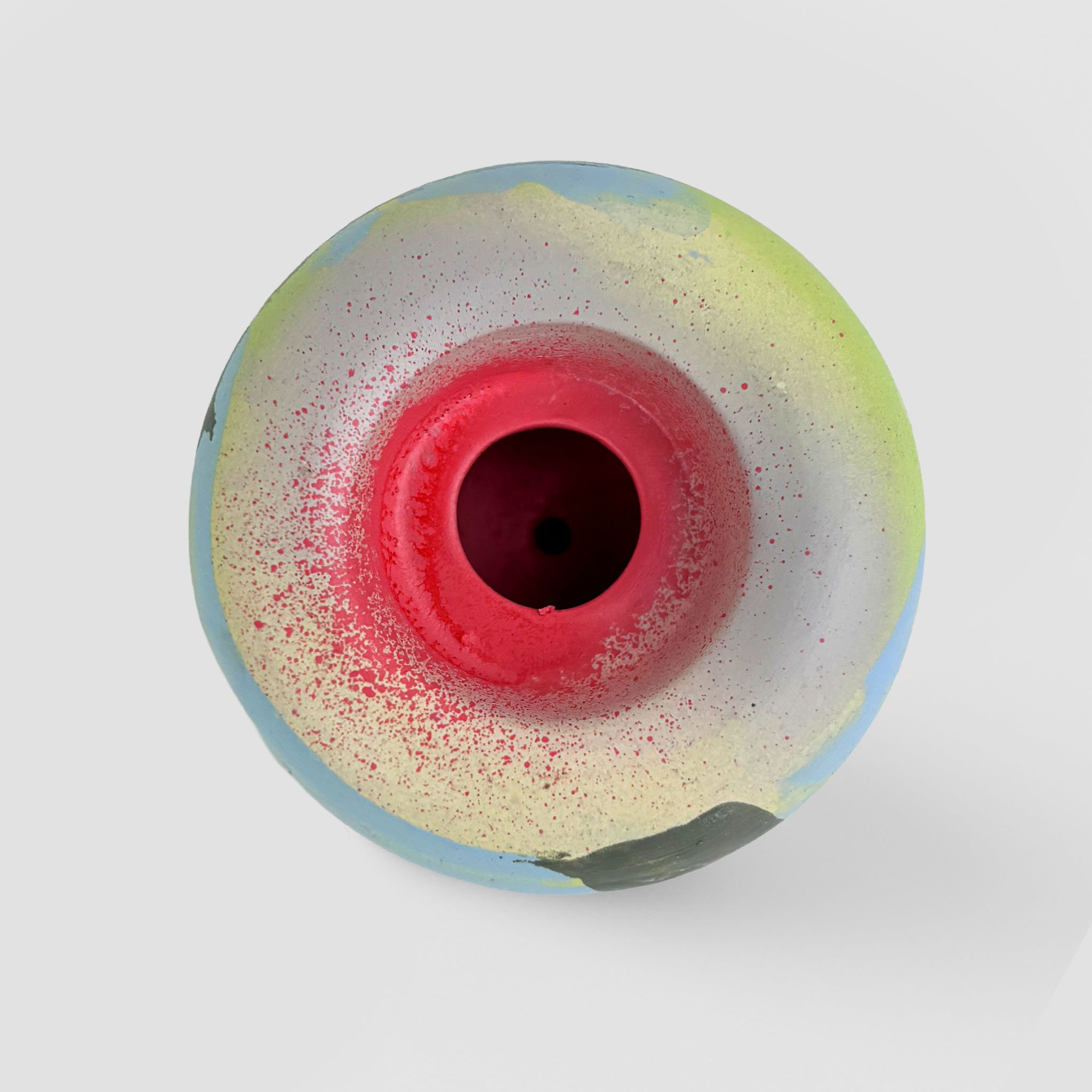 Top view of a colorful ball with red, white, and blue paint splatters on a white background.