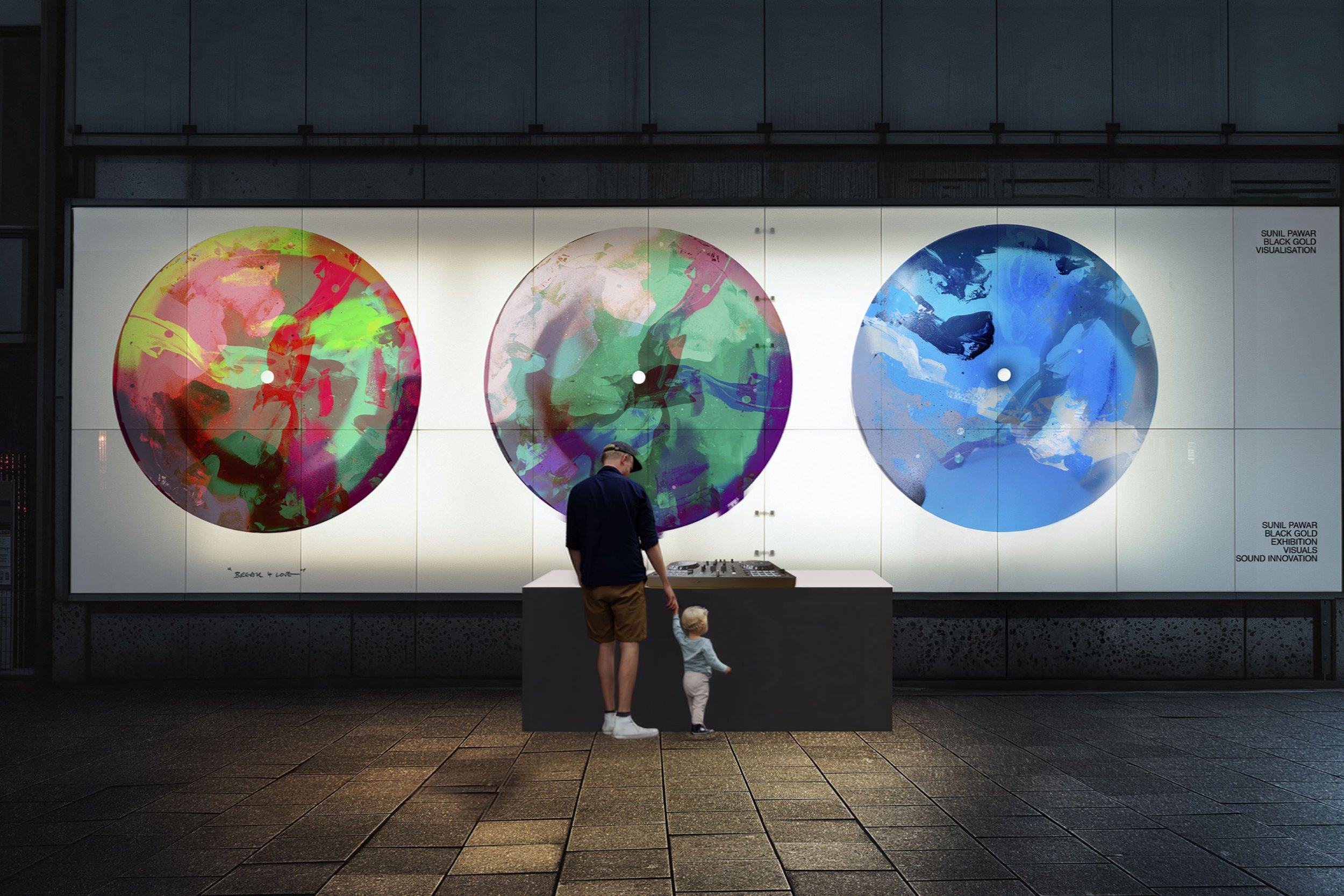 A person and a child standing in front of a large, colorful art installation featuring three circular, abstract paintings on a white wall, with a DJ mixer on a table in front of them.