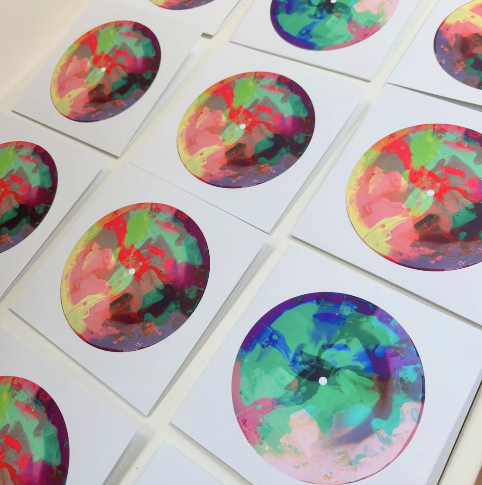 Multiple sheets of paper with abstract, multicolored circular designs resembling watercolor paintings.