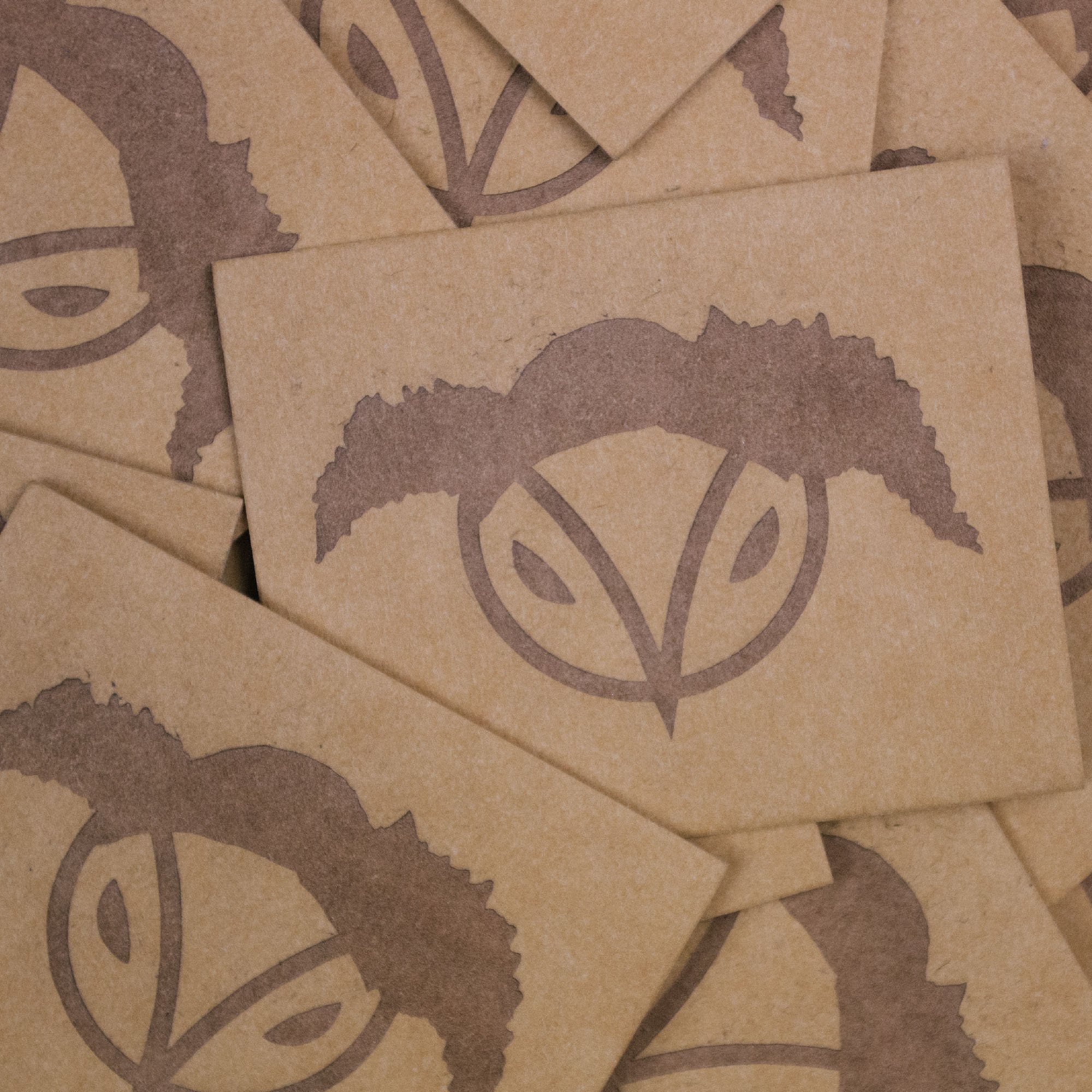 Multiple beige paper squares with brown leaf and circle logo design.