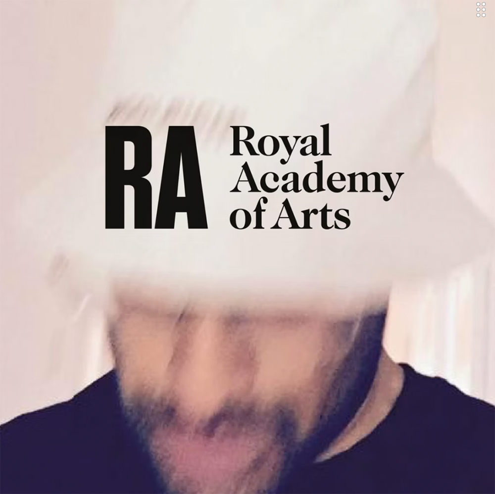 A person holding a card or sign with the logo and text of the Royal Academy of Arts, partially covering their face